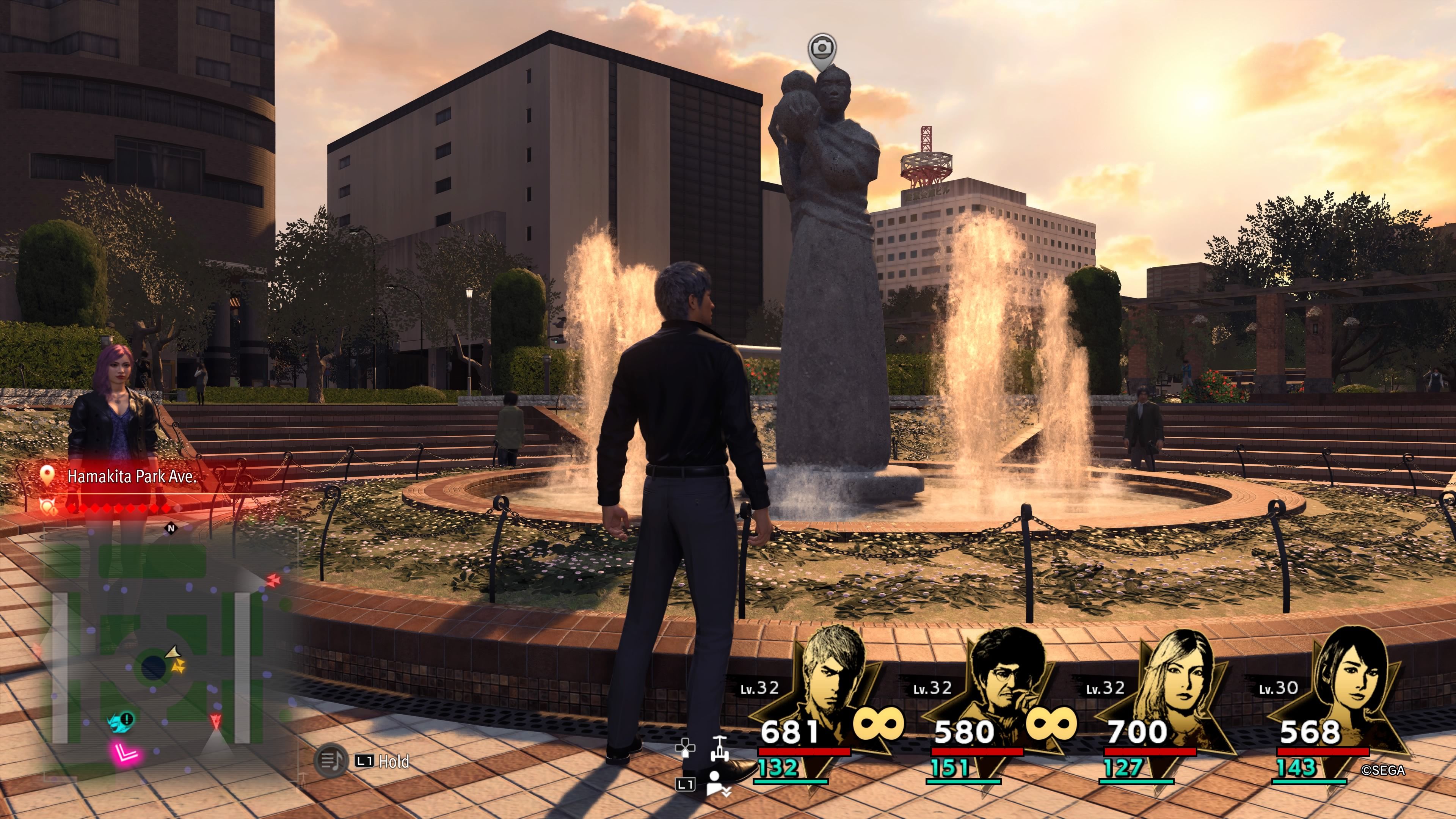 Kiryu and Seonhee standing in front of the Hamakita Park Fountation in Hamakit Park in Like A Dragon: Infinite Wealth.