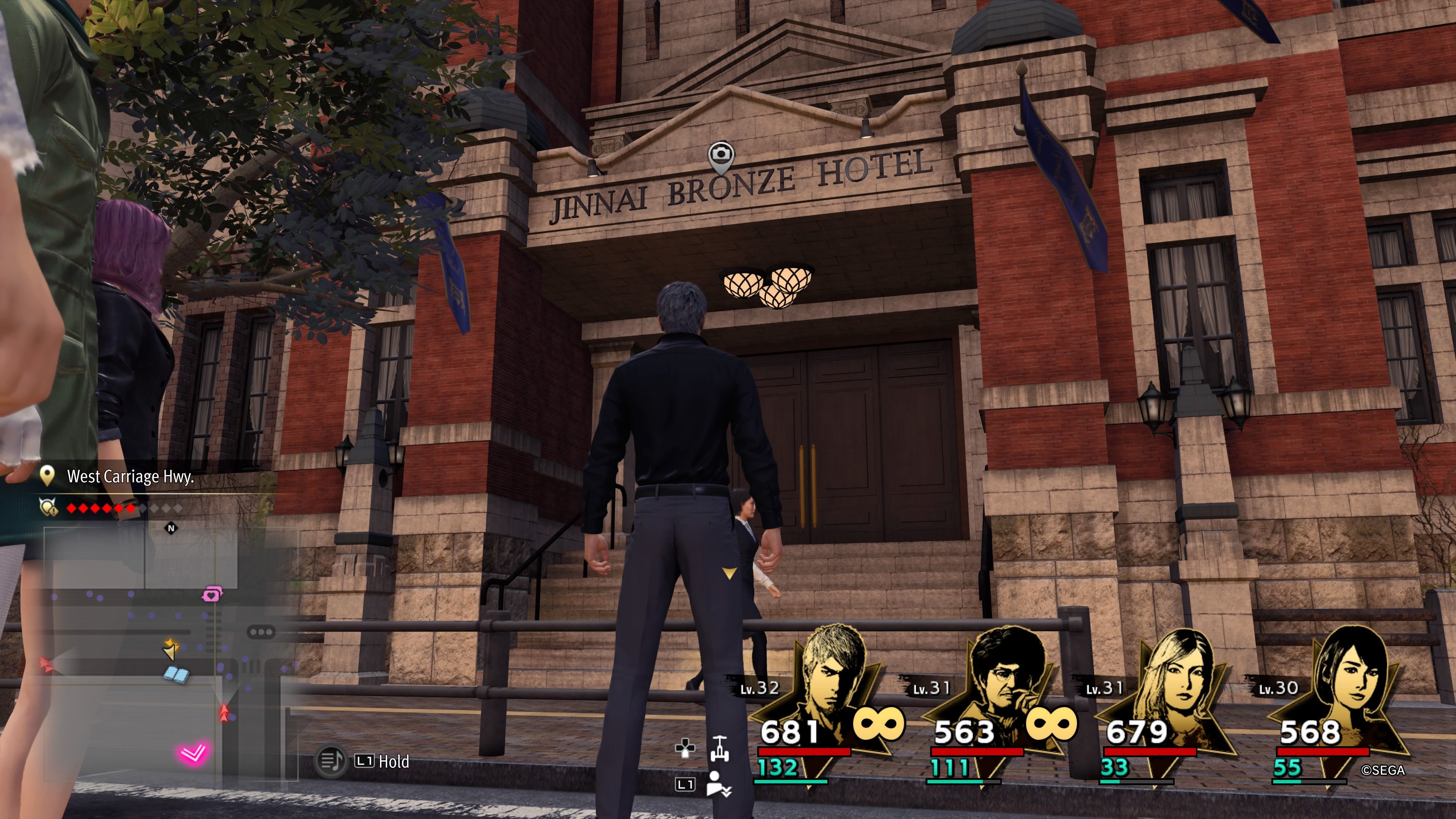 Kiryu standing in front of a large brick hotel called Jinnai Bronze Hotel in Like A Dragon: Infinite Wealth.