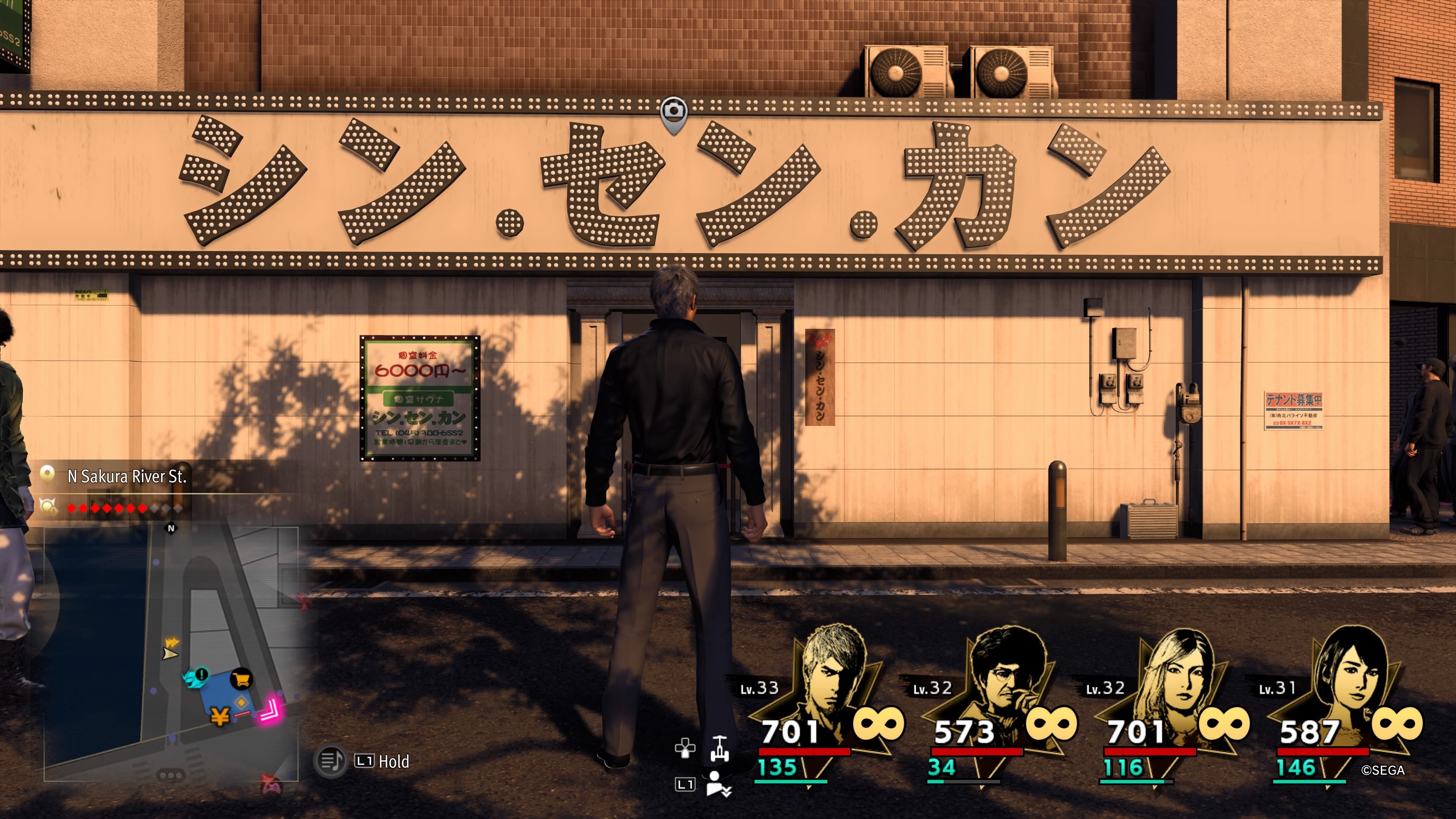 Kiryu standing in front of the Private Sauna Shin Sen Kan building in downtown Yokohama in Like A Dragon: Infinite Wealth