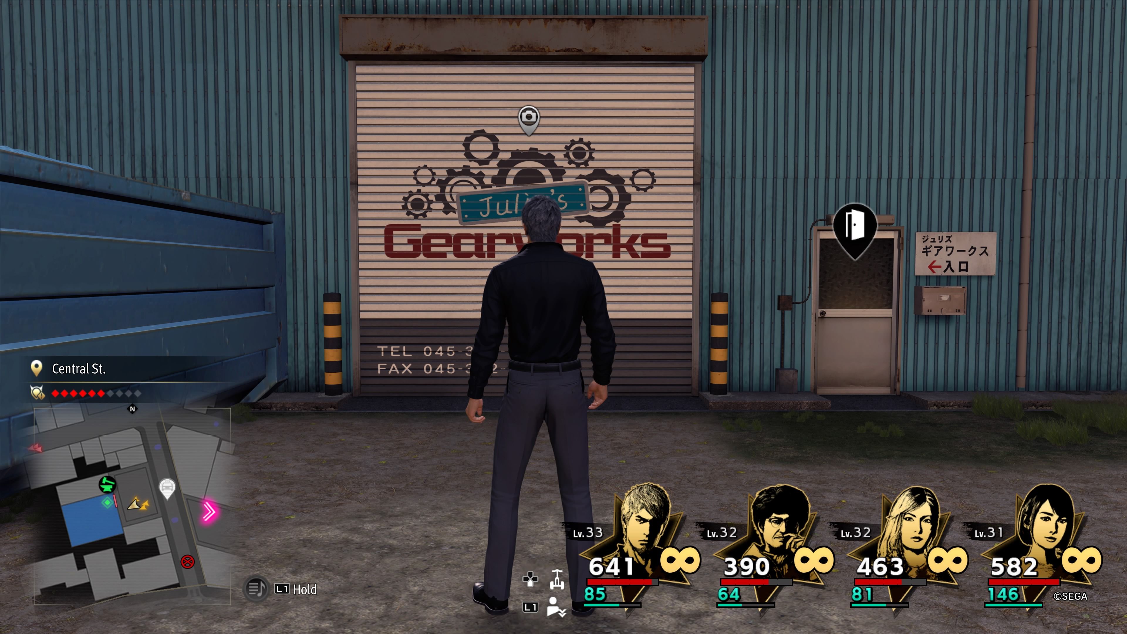 Kiryu standing in front of the garage of Julie's Gearworks in downtown Yokohama in Like A Dragon: Infinite Wealth.