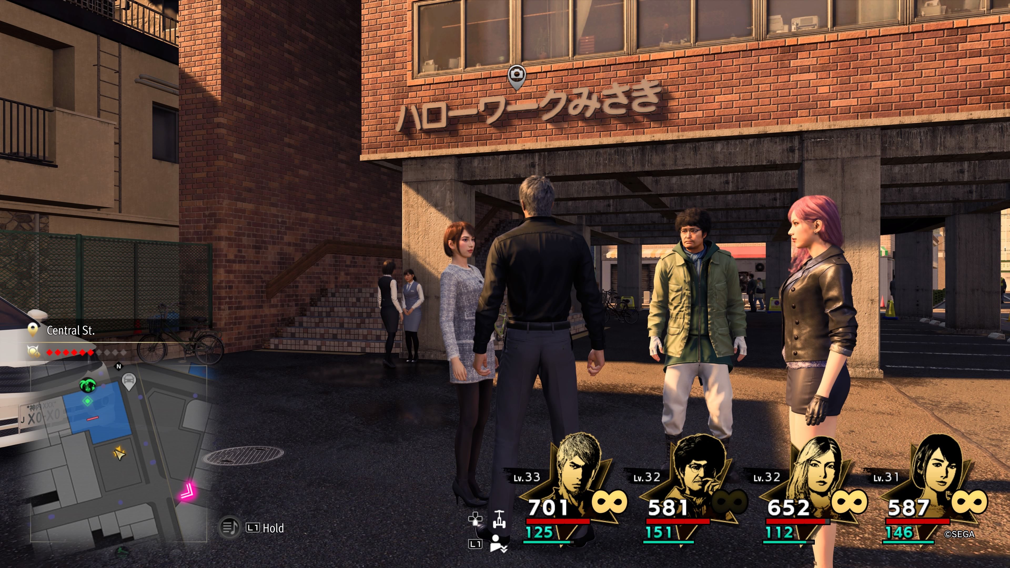 Kiryu, Seonhee, Saeko, and Nanba standing beneath the entrance sign to Hello Work in Like A Dragon: Infinite Wealth.