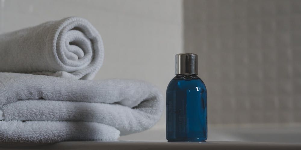 Generic Glass Bottle Of Shampoo Next To A Pile Of Towels