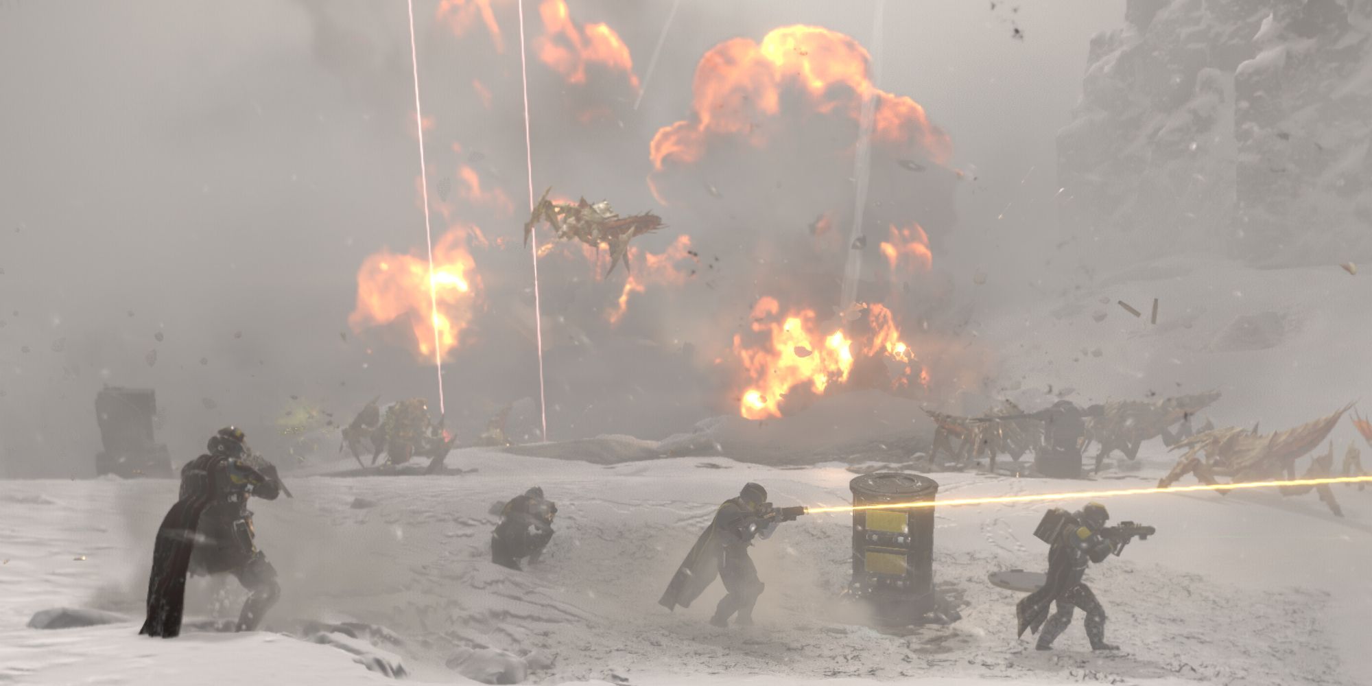 a squad of four fights terminids in the snow while large explosions go off in the background in helldivers 2
