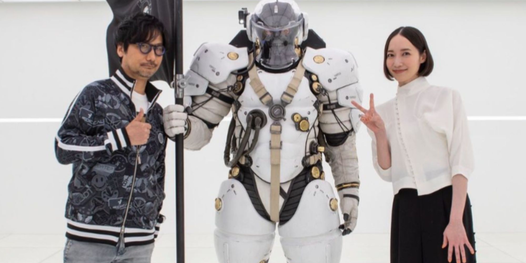 Hideo Kojima with Perfume singer Ayano Omoto in front of the Kojima Productions Ludens Mascot