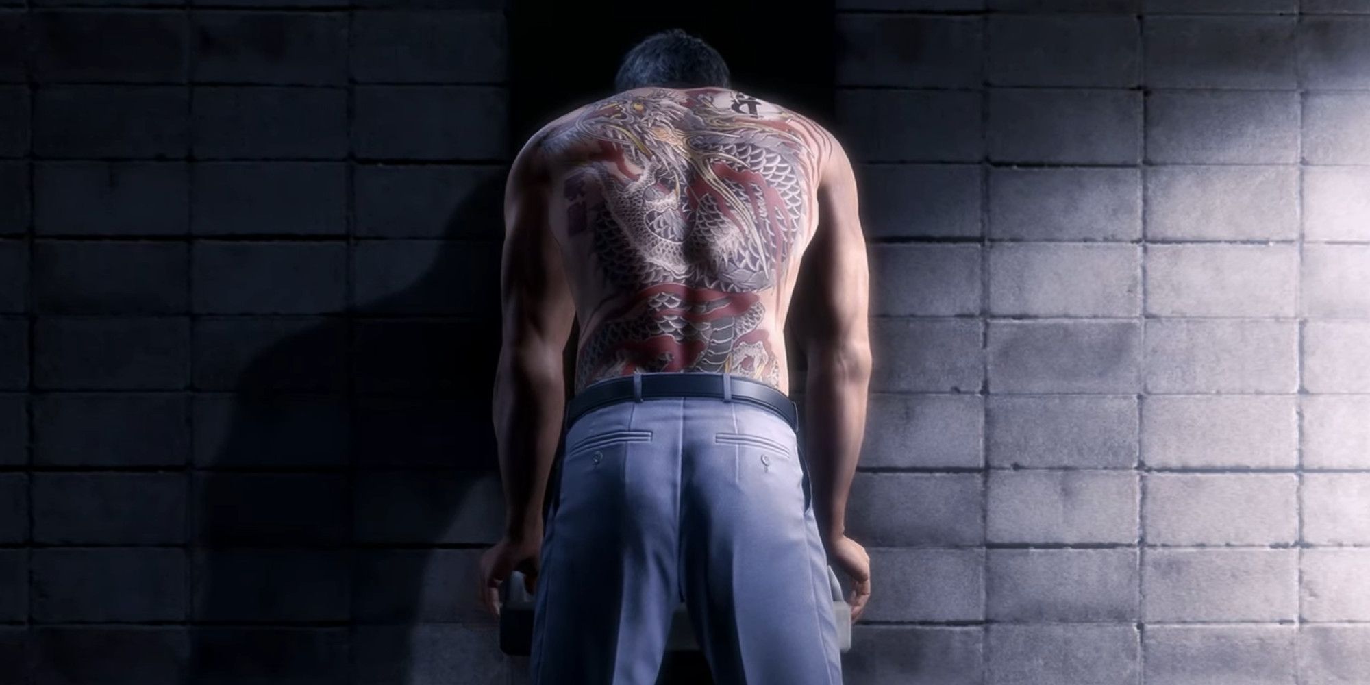 Kiryu hunched over a bathroom sink shirtless with his back tattoo on full display