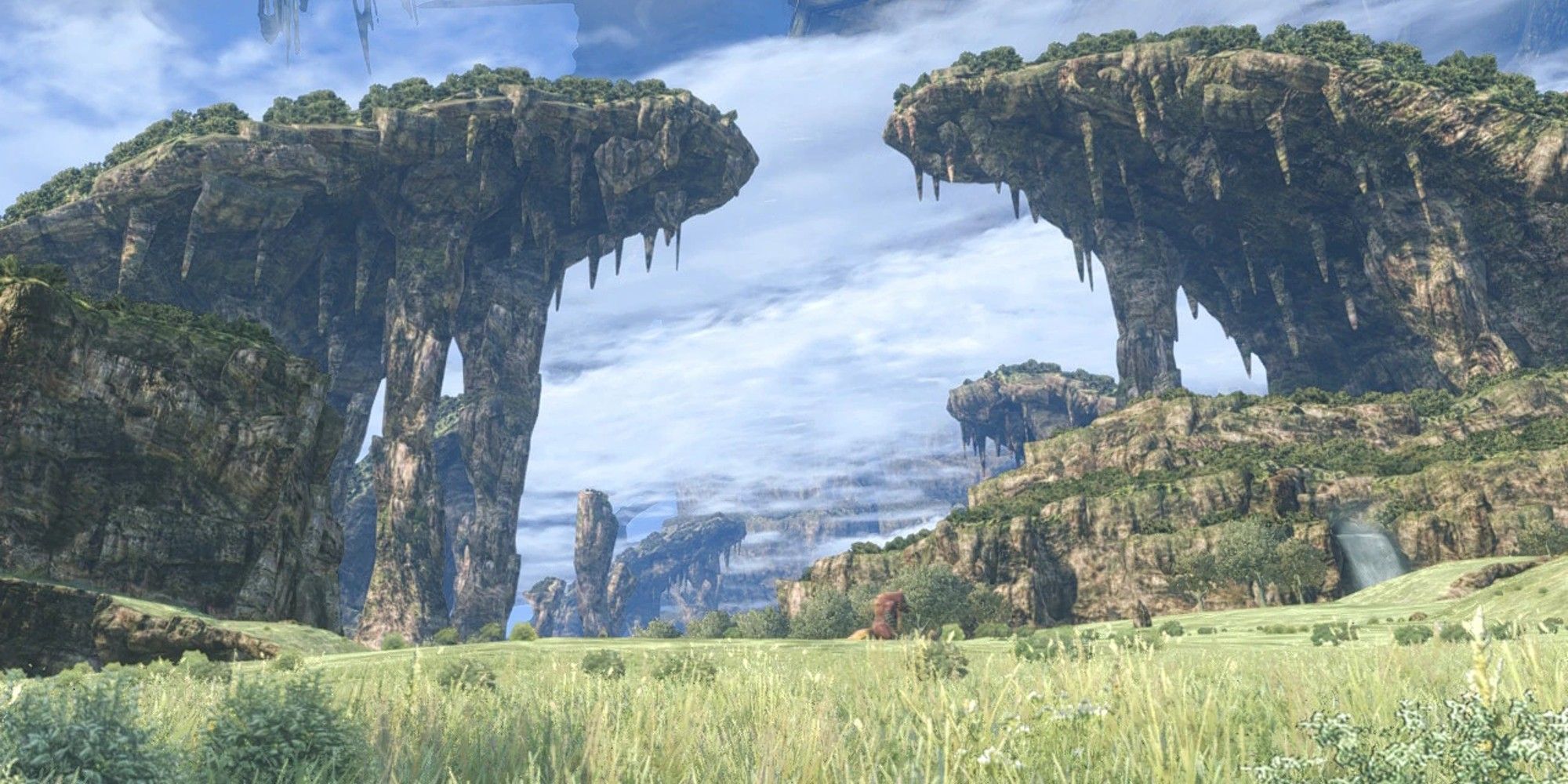Two large rock formations face each other over grassy plains. 