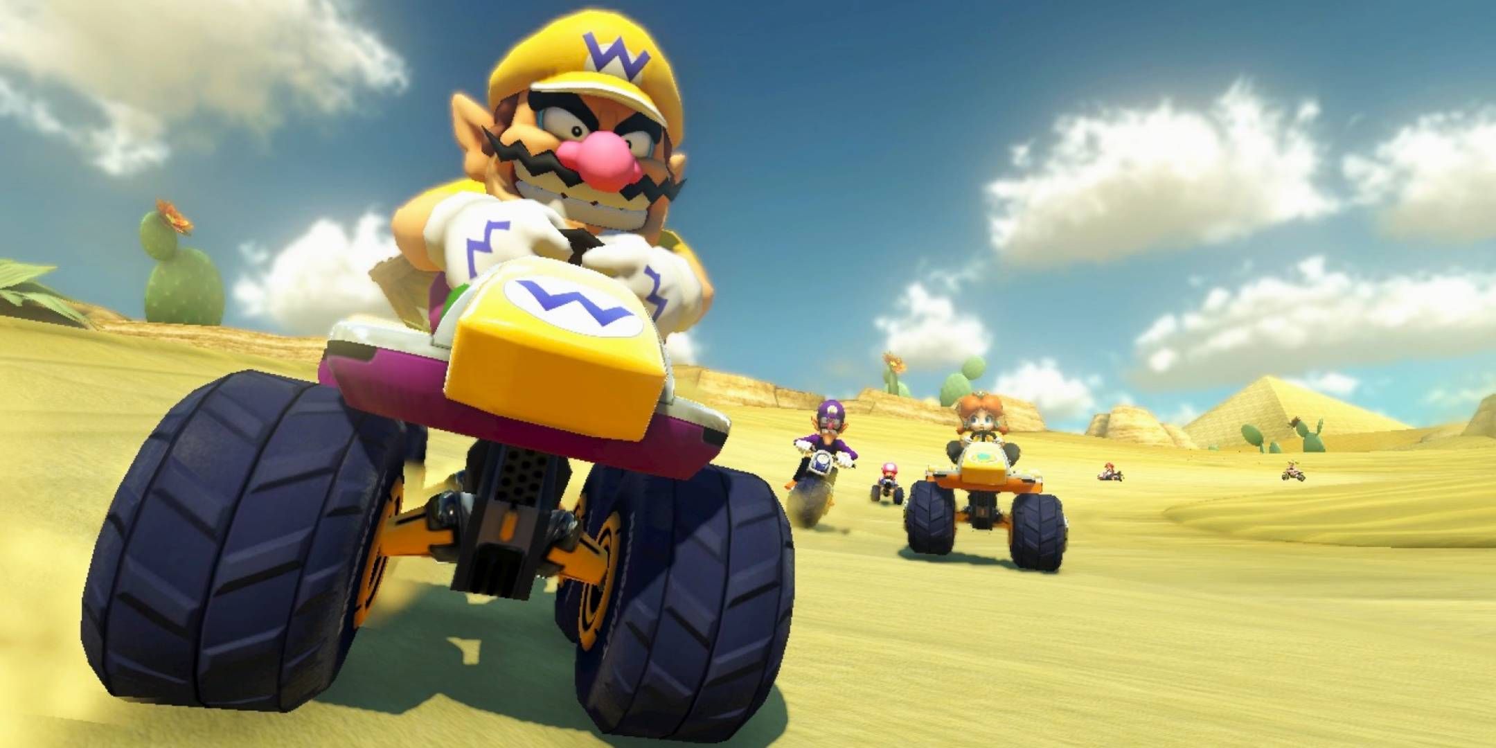 Mario Kart 8 Wario driving with big wheels in front of Waluigi and Daisy