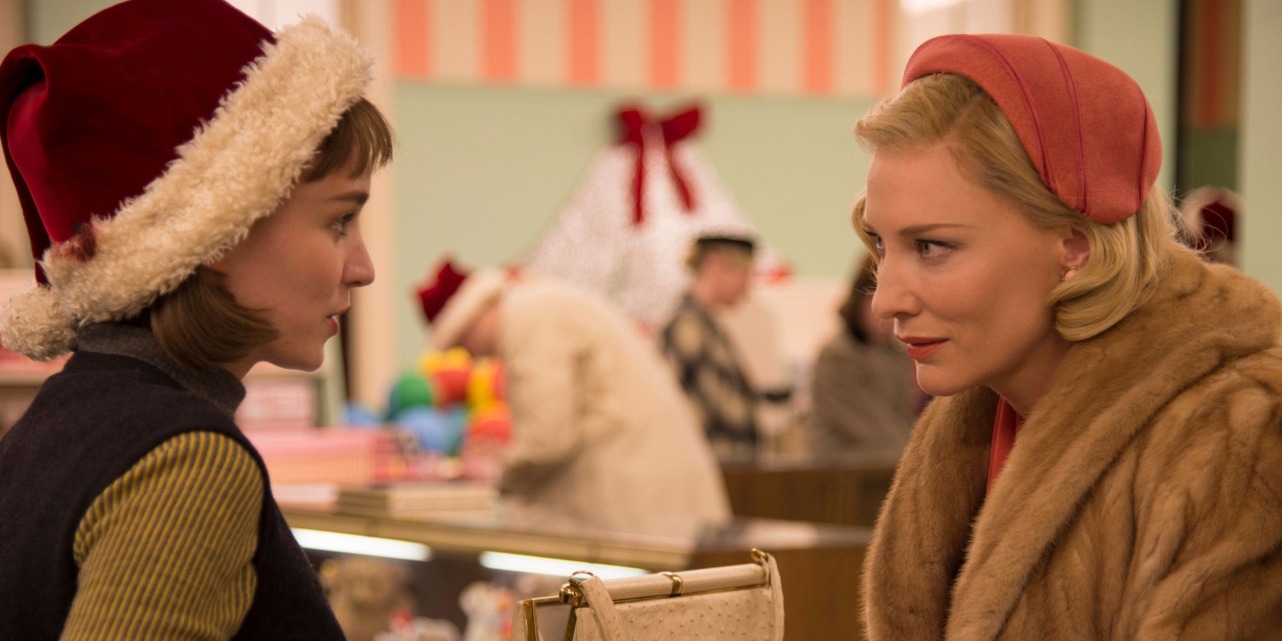 Two women speak in a department store. One is wearing a santa hat, the other finely dressed in a fur coat.
