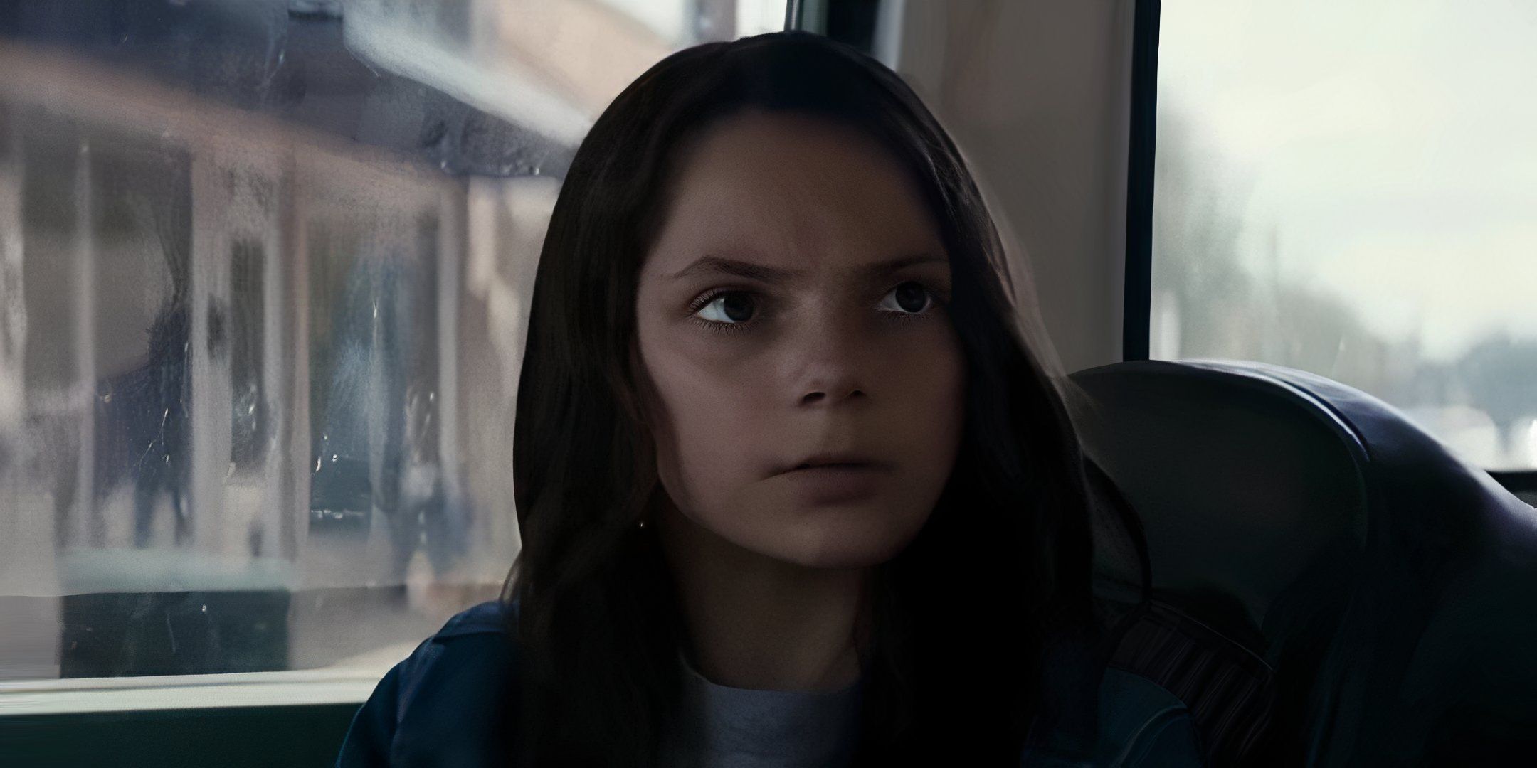 Logan movie image showing Laura taking to Logan while sitting in a car.