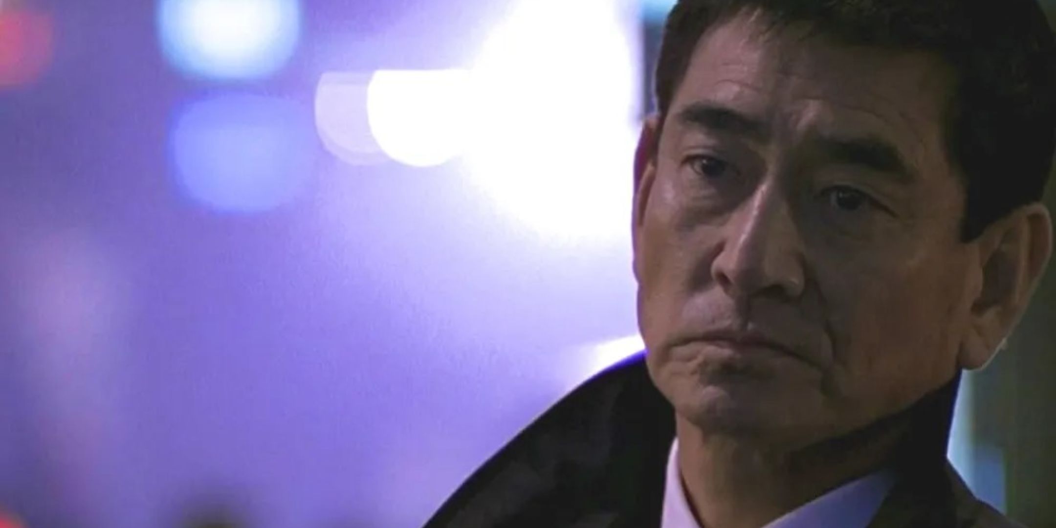 Ken Takakura looking sorrowful in a suit.