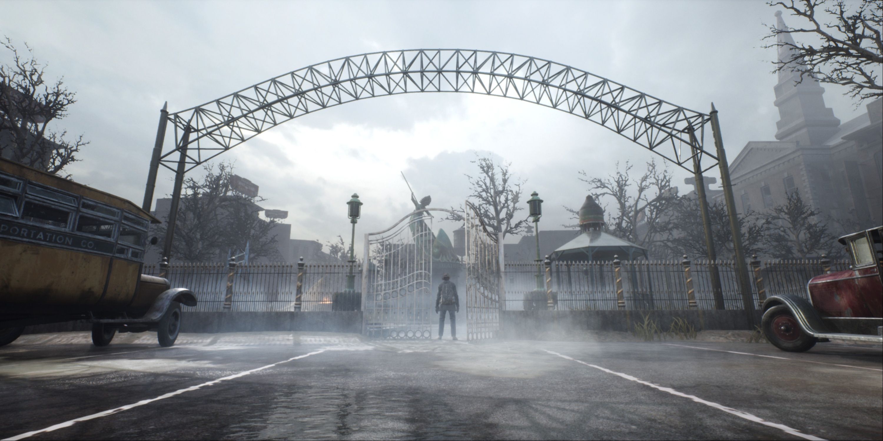 The Main Protagonst In The Sinking City Standing Over A Gated Archway With A Fog Rolling In And Classic Cars Seen Behind Him.