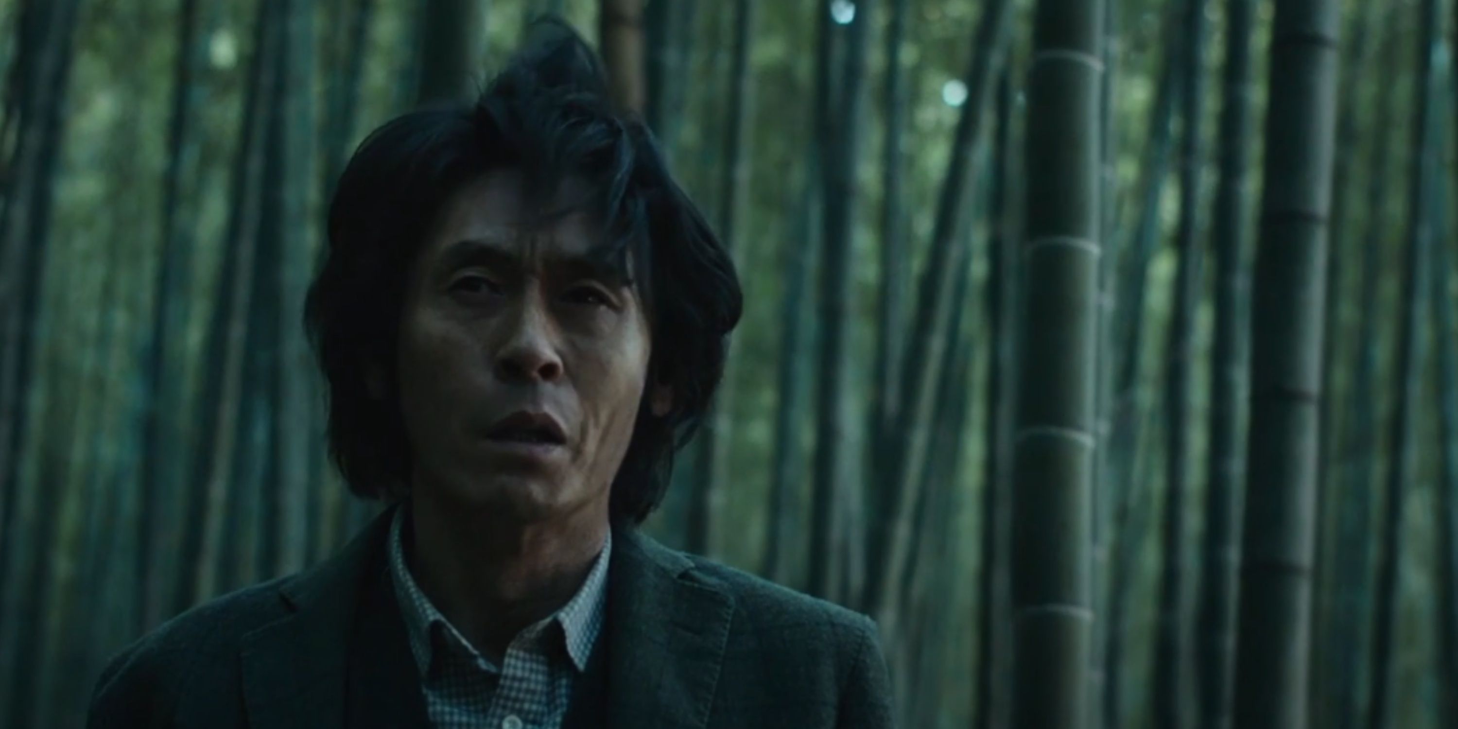 Byung-soo stands in a bamboo forest suffering from facial twitches due to his Alzheimer's in Memoir Of A Murderer.
