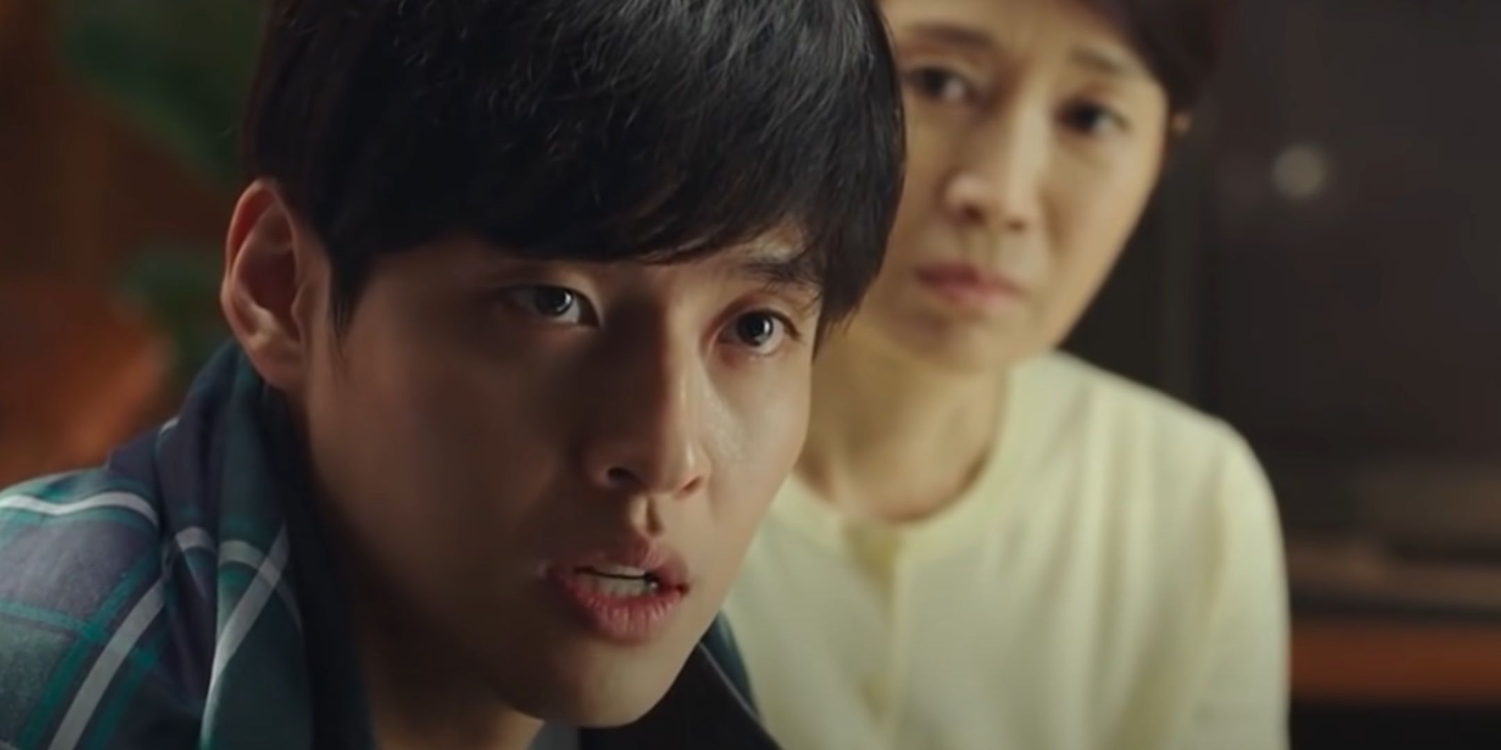 Jin-seok looks tense as he speaks to his police; his mother sits beside him in Forgotten.