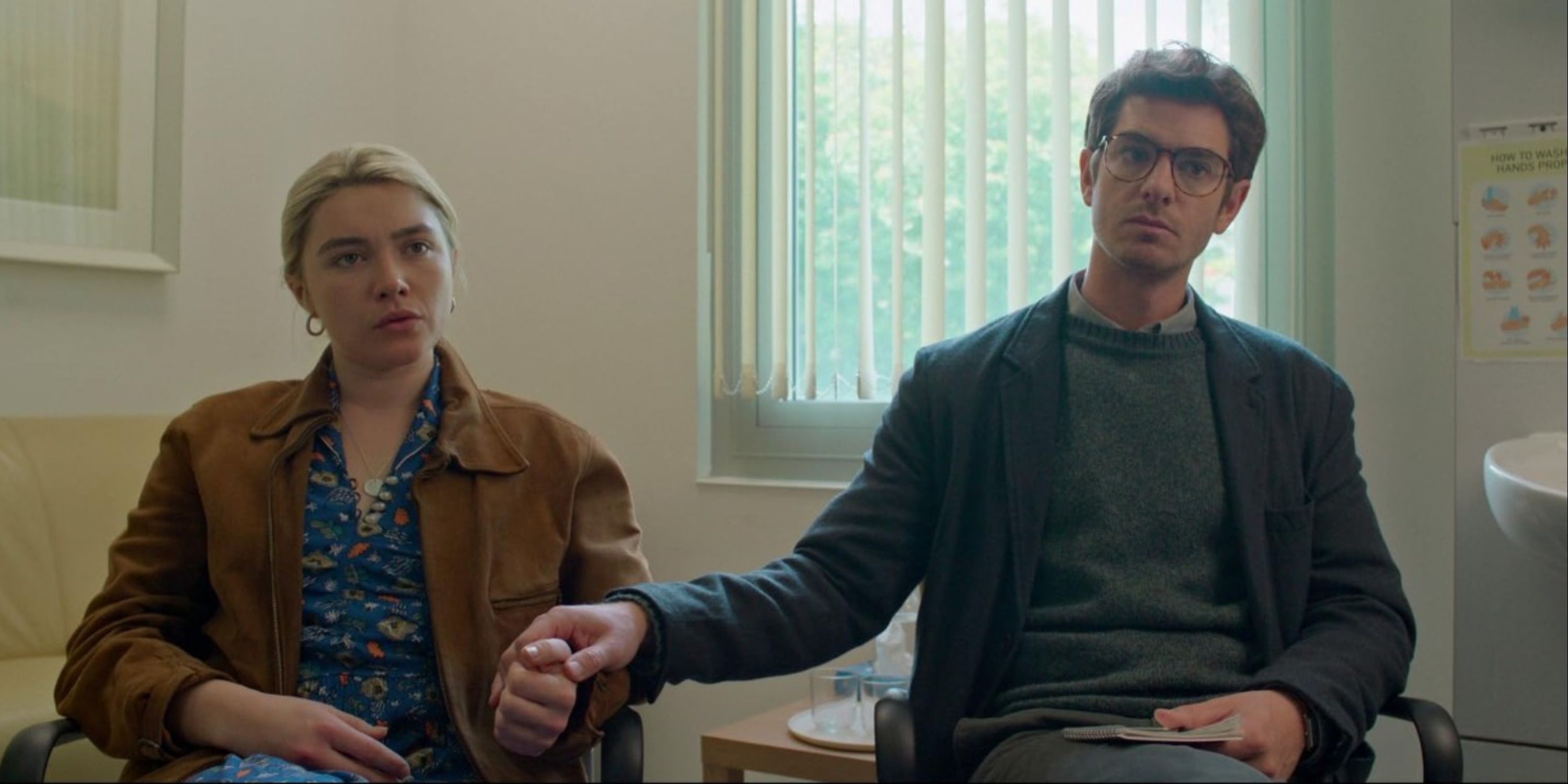 Andrew Garfield holding Florence Pugh's hand as they hear from the doctor in We Live in Time.