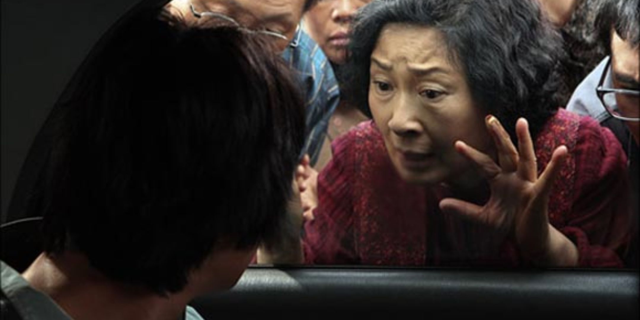 A mother looks at her son in the back of a cop car. 