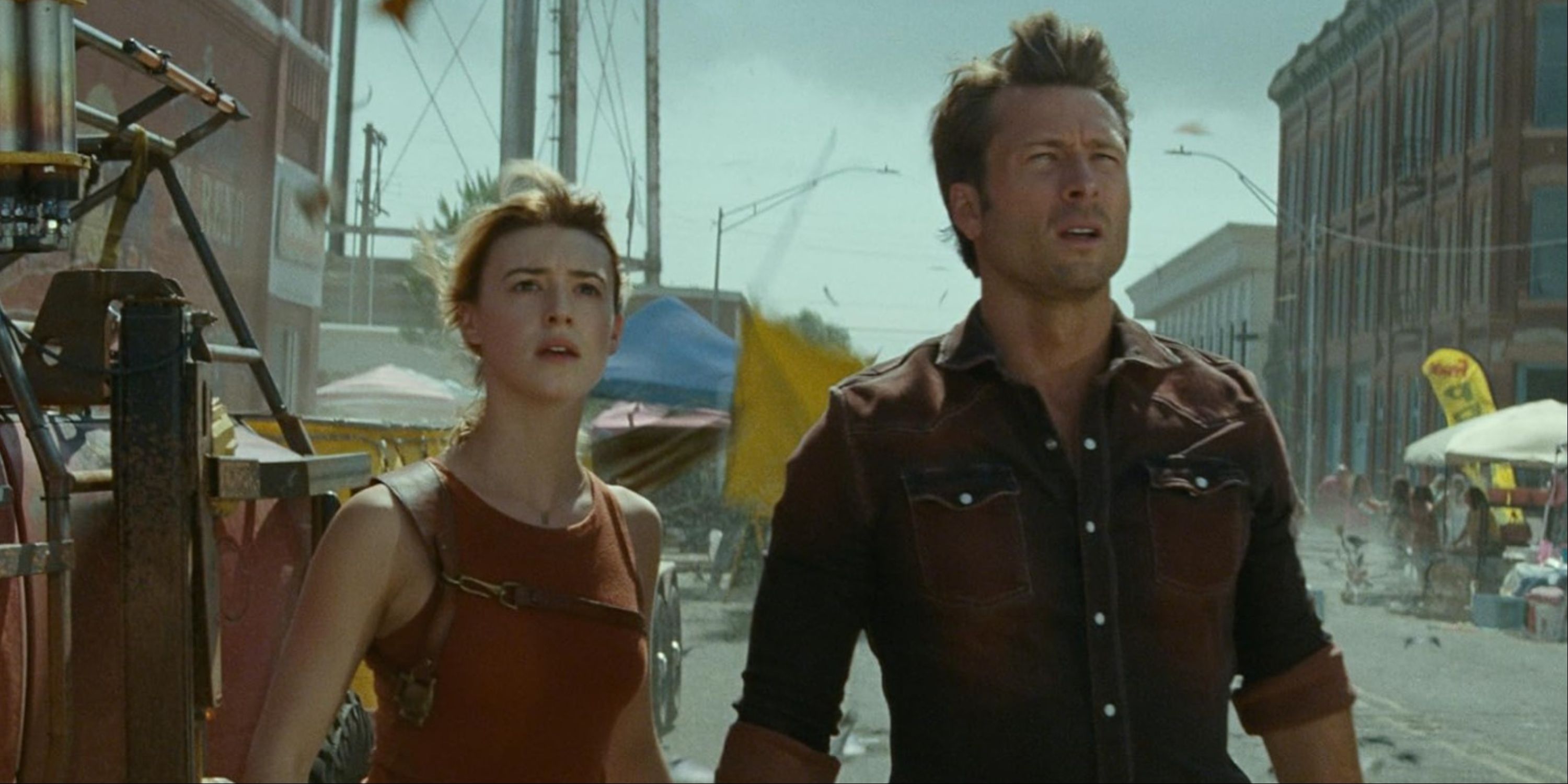 Daisy Edgar-Jones and Glen Powell in the middle of a street looking up at a twister in Twisters.