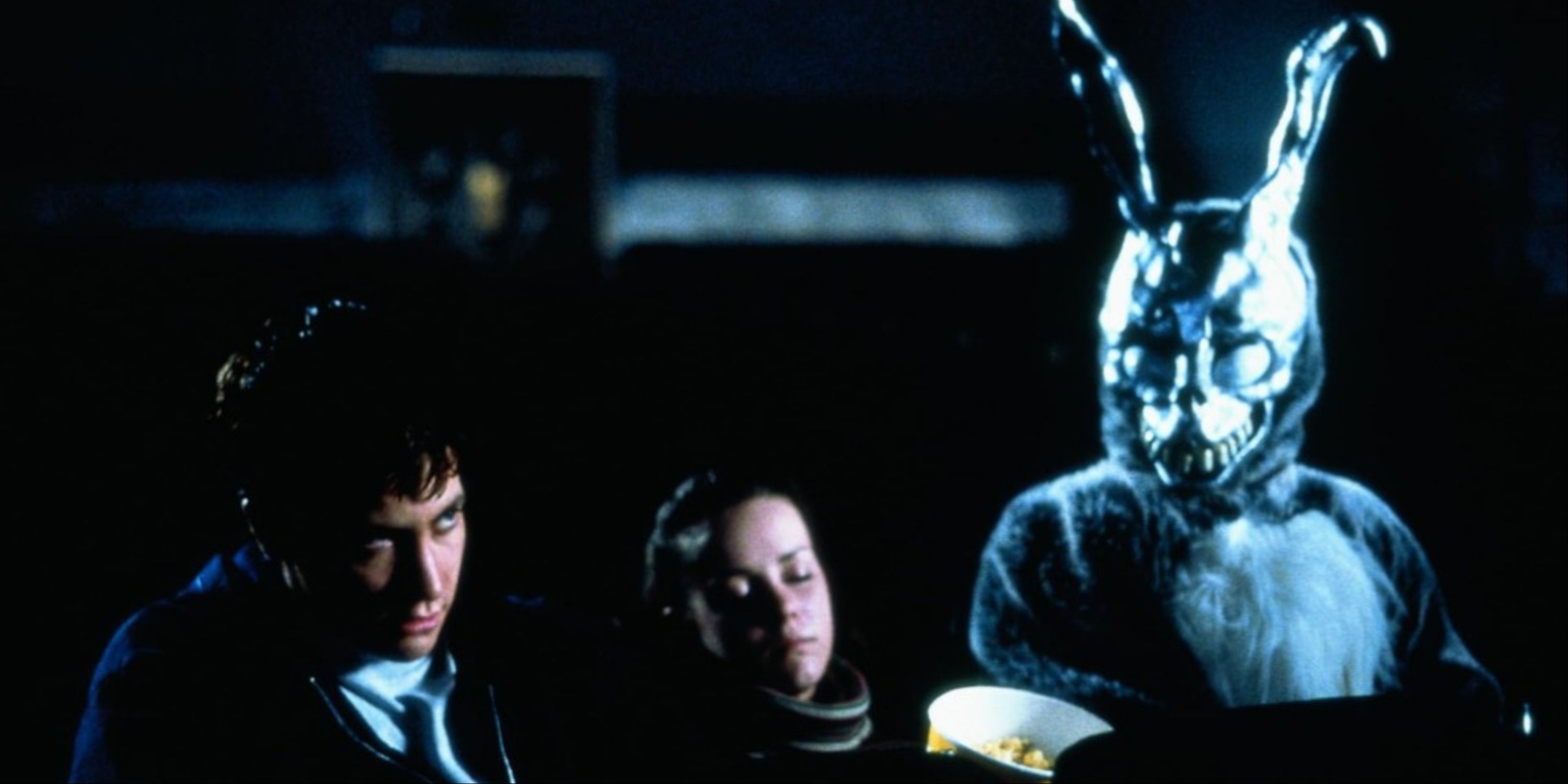 Jake Gyllenhaal, Jena Malone, and the humanoid bunny seated together at a theater in Donnie Darko.
