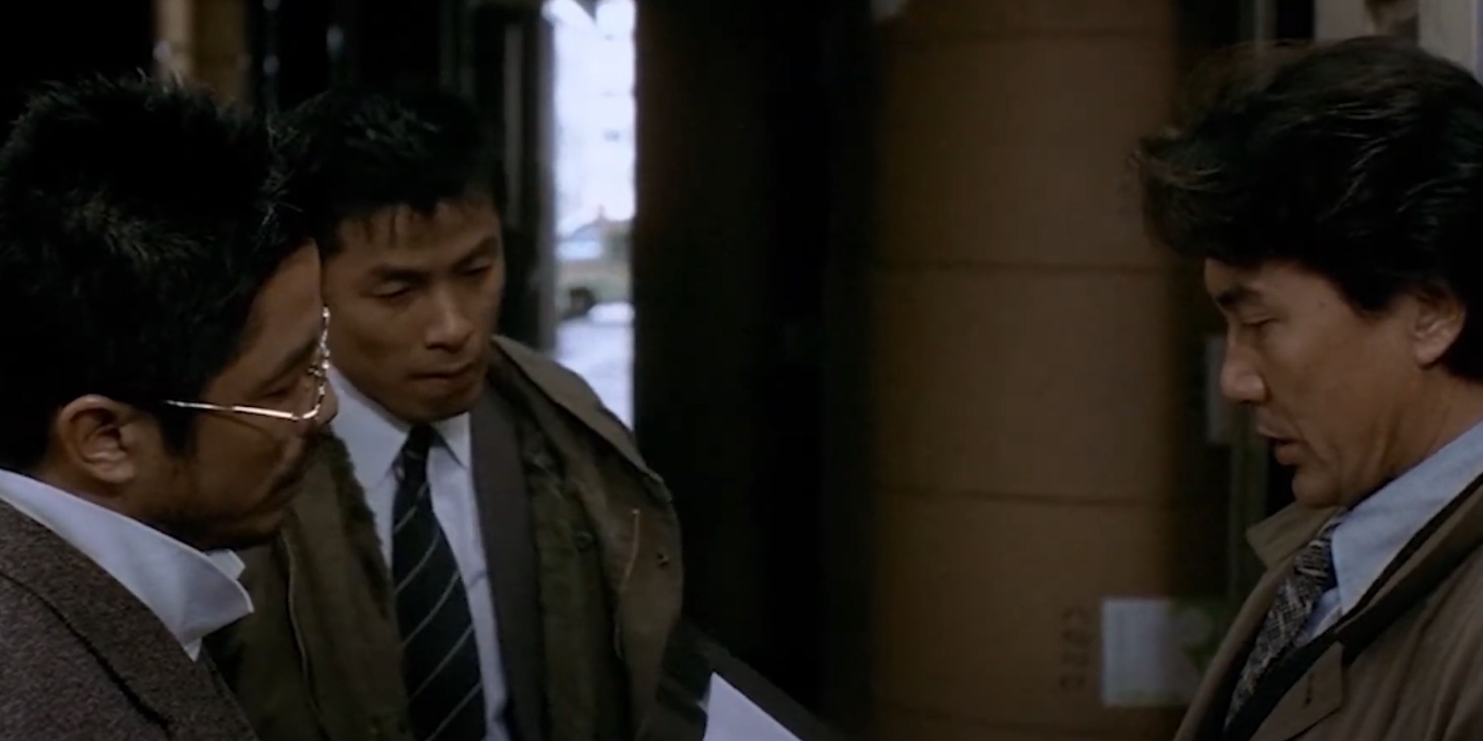 Takabe pores over a case while Sakuma and an officer looks on in Cure.