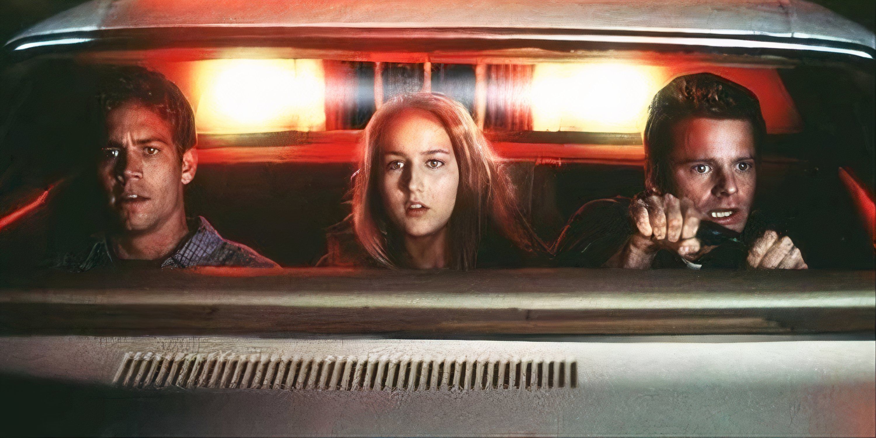 Paul Walker, Leelee Sobieski, and Steve Zahn seated in a car with a truck's headlights behind them in Joy Ride.