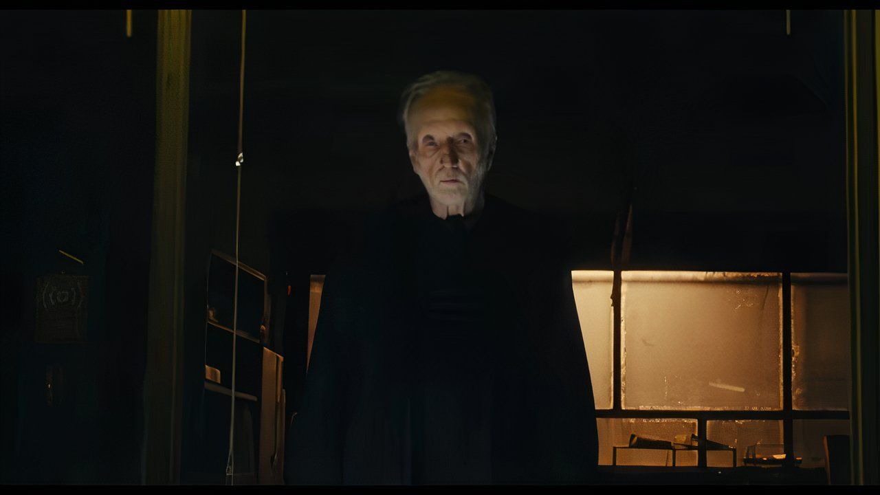 Tobin Bell as Jigsaw, standing on a raised platform in Saw 10.