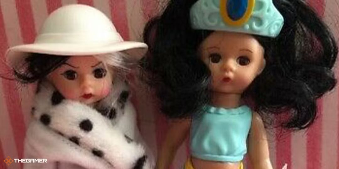 Two Madam Alexander dolls, one Cruella DeVille and the other Jasmine, sit against a wall.