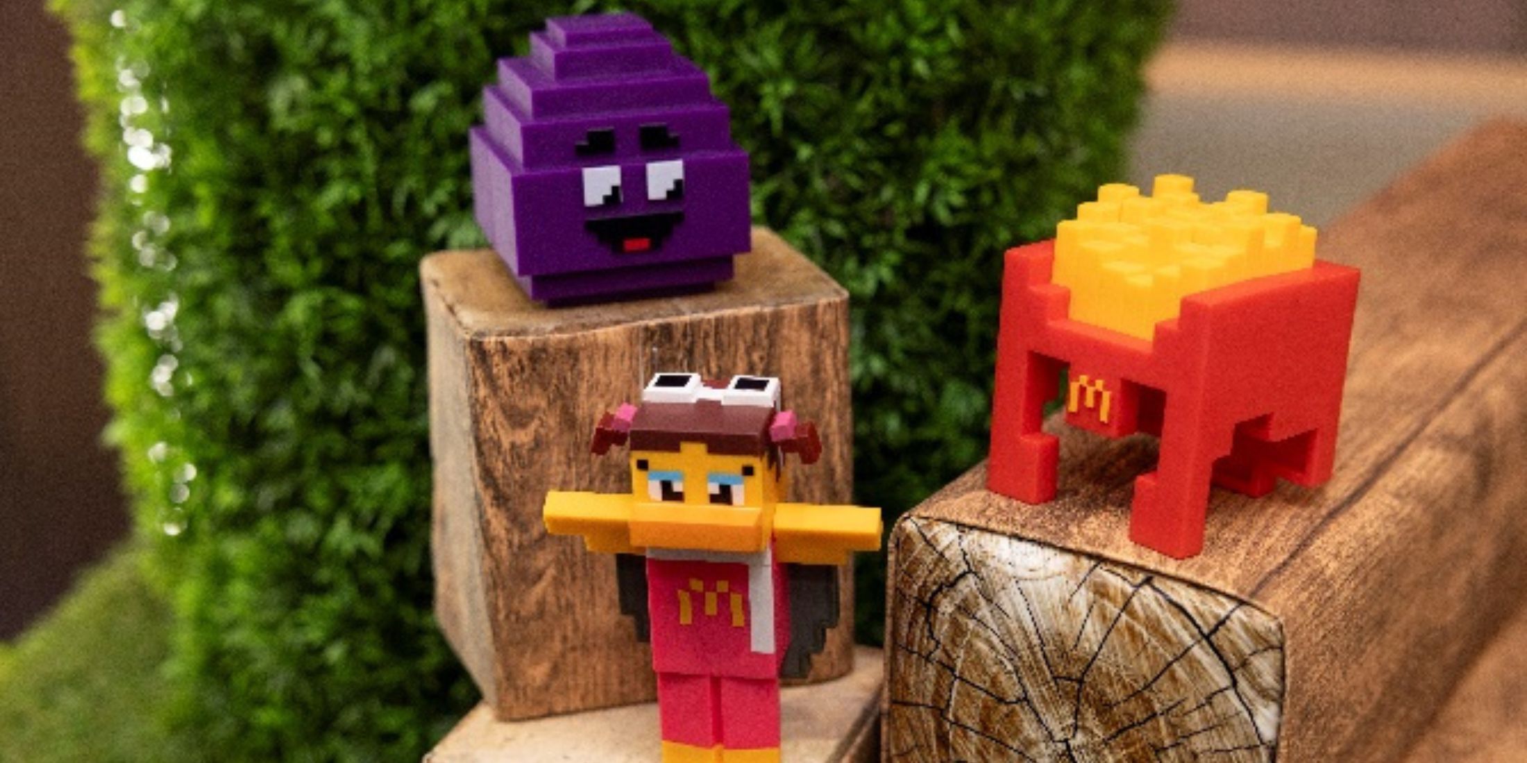 Three Minecraft McDonalds toys on a wood block. 