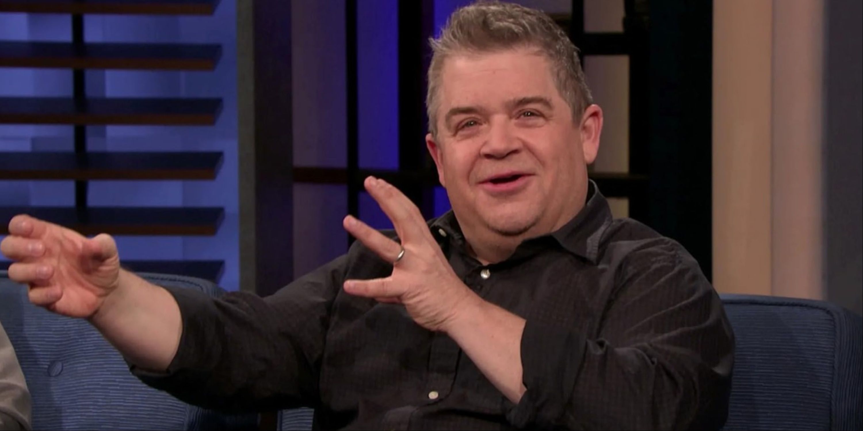 Patton Oswalt motioning with his hands during an interview on a late-night show.