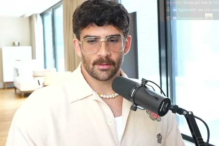Hasan Piker speaking on stream. He is wearing white and there is a microphone in front of him