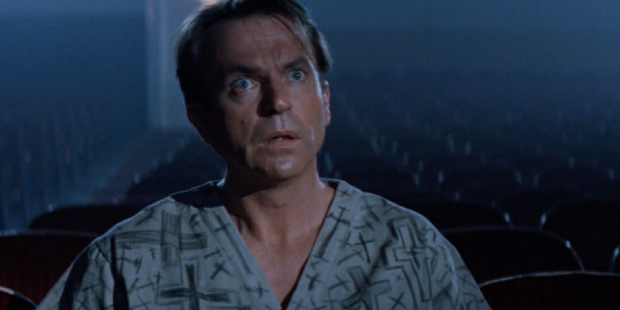 The main charcter in a robe in a theater looking awestruck in In The Mouth of Madness.