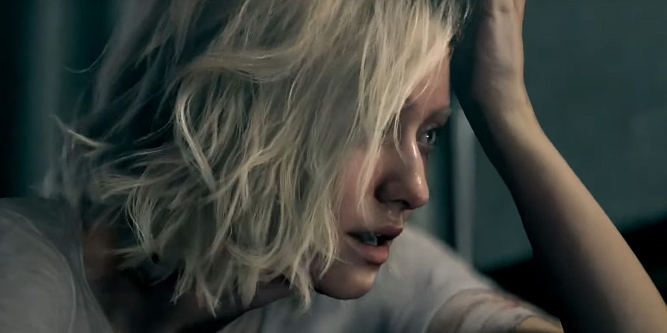 A blonde woman holding her head with her left hand.
