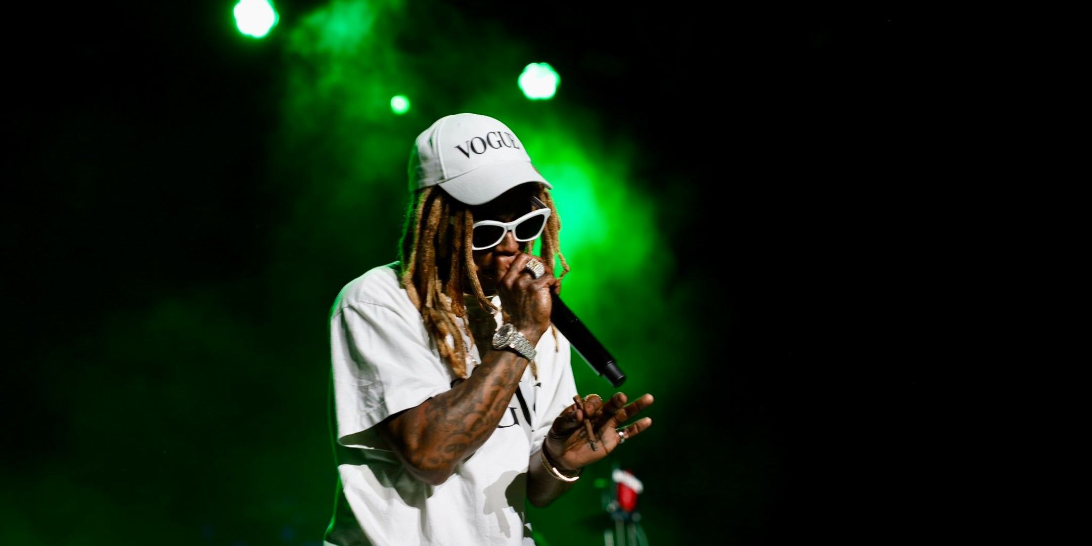 Lil Wayne rapping on stage with a Vogue hat.