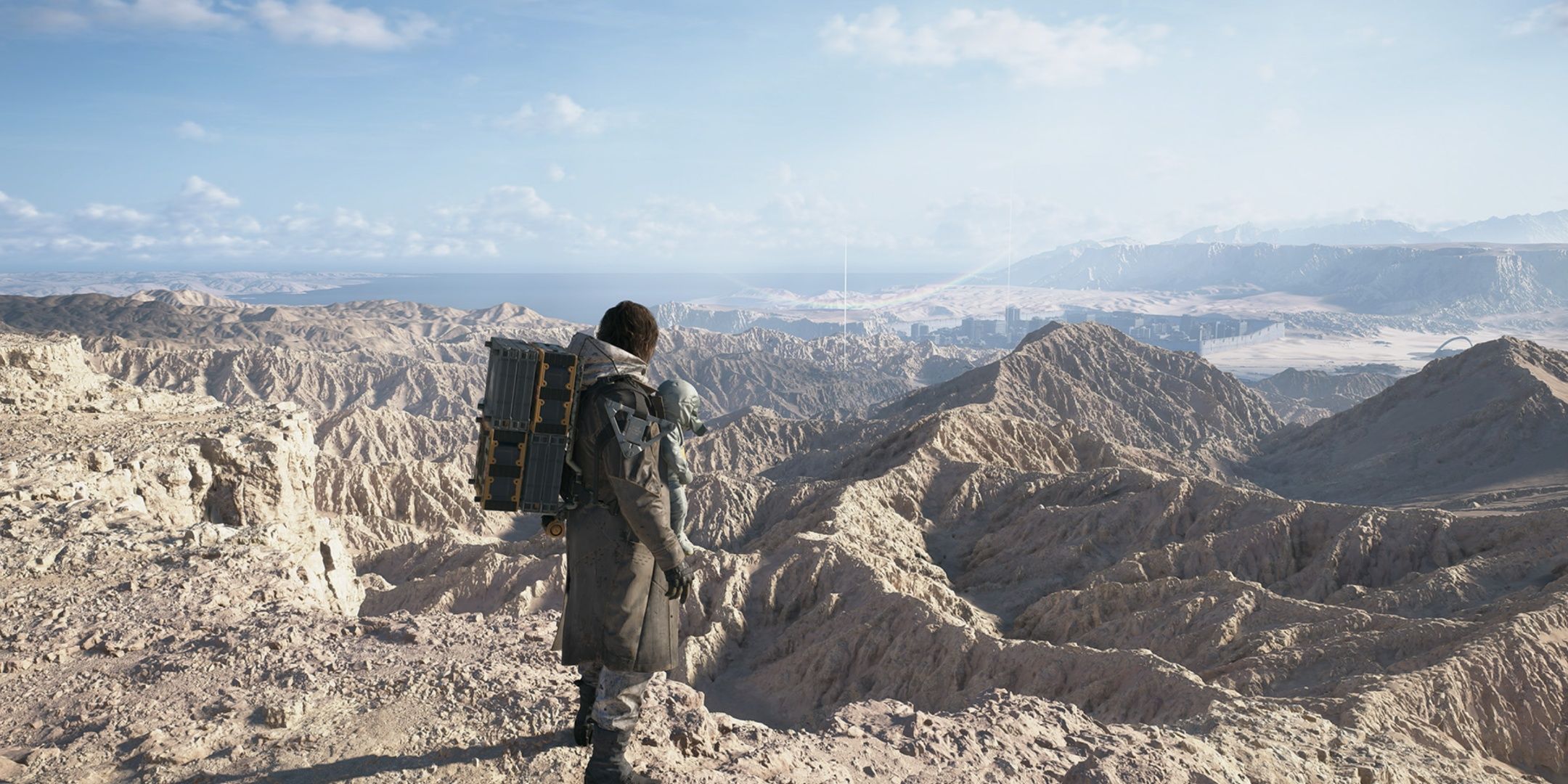 Sam stands atop a mountain range in Mexico ready to traverse down it in Death Stranding 2. 