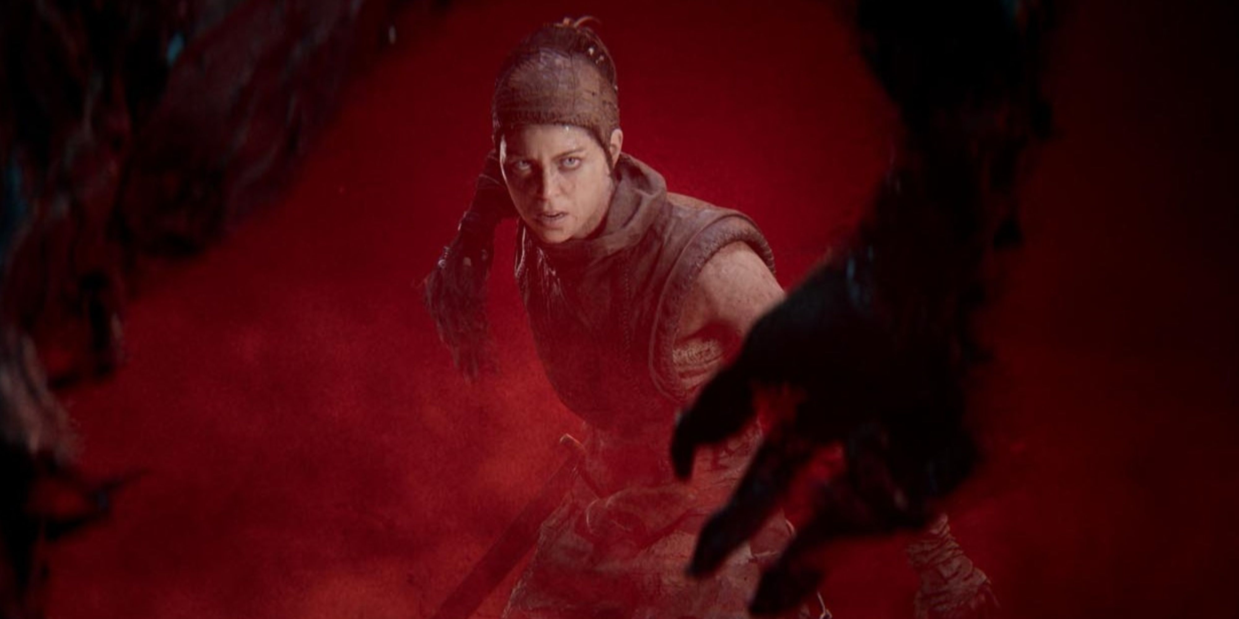 senua in hellblade 2 with a creep black hand in the foreground.