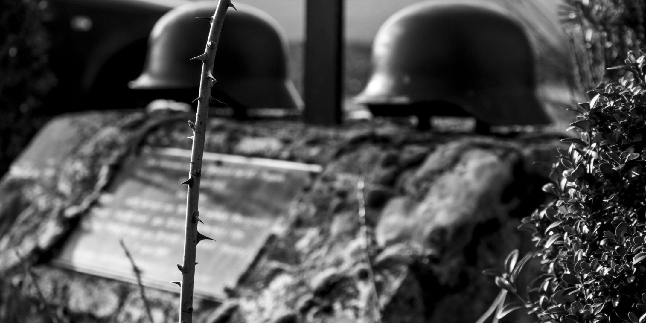 A tombstone with soldiers' helmets on top of it.