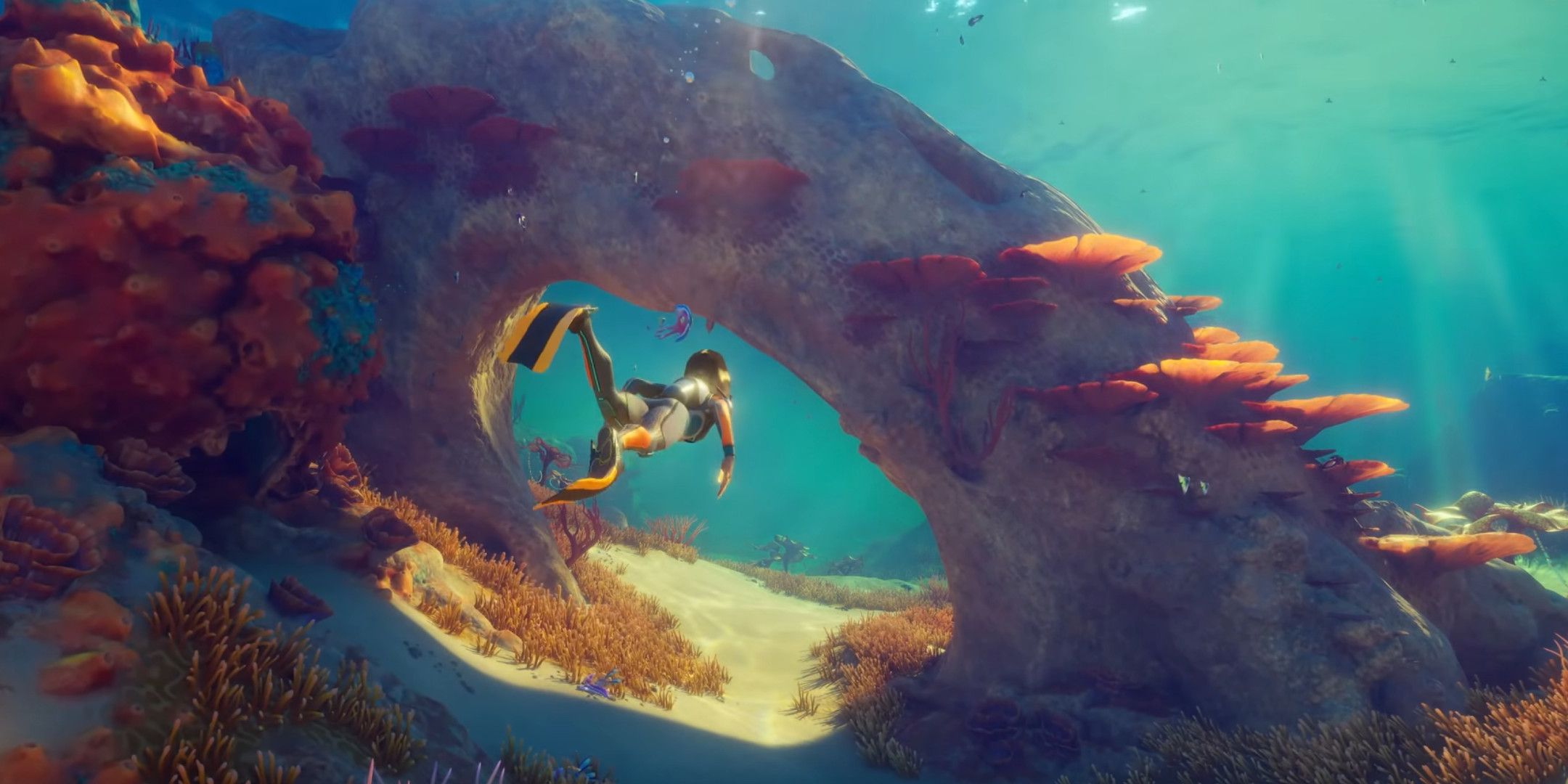 A diver swimming through an underwater arch.