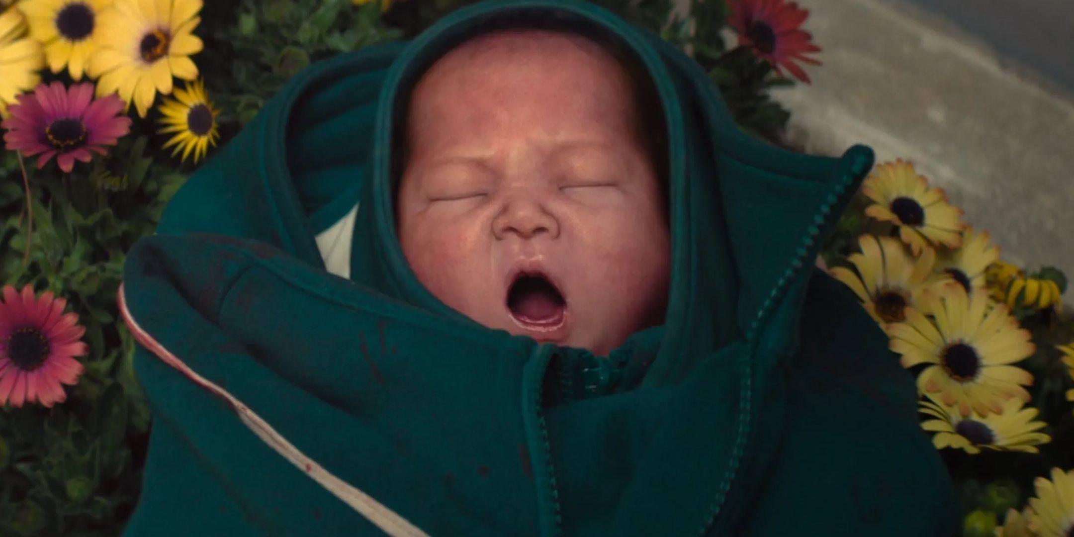 CGI baby in Squid Game with its mouth open lying on a flower bed.