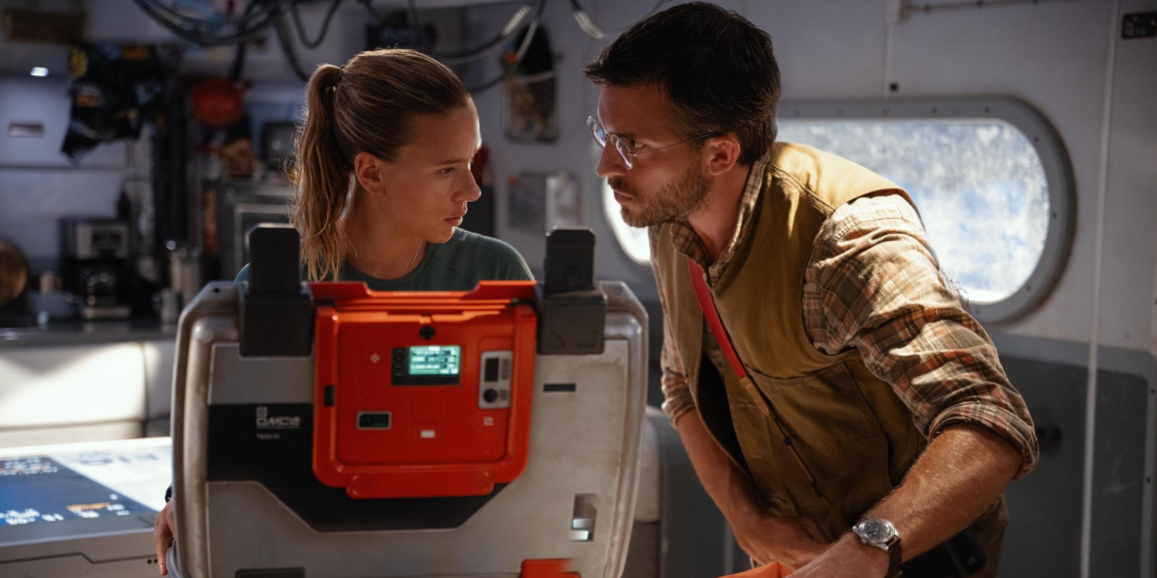 scarlett johansson and an actor in jurassic world rebirth standing over an open briefcase.