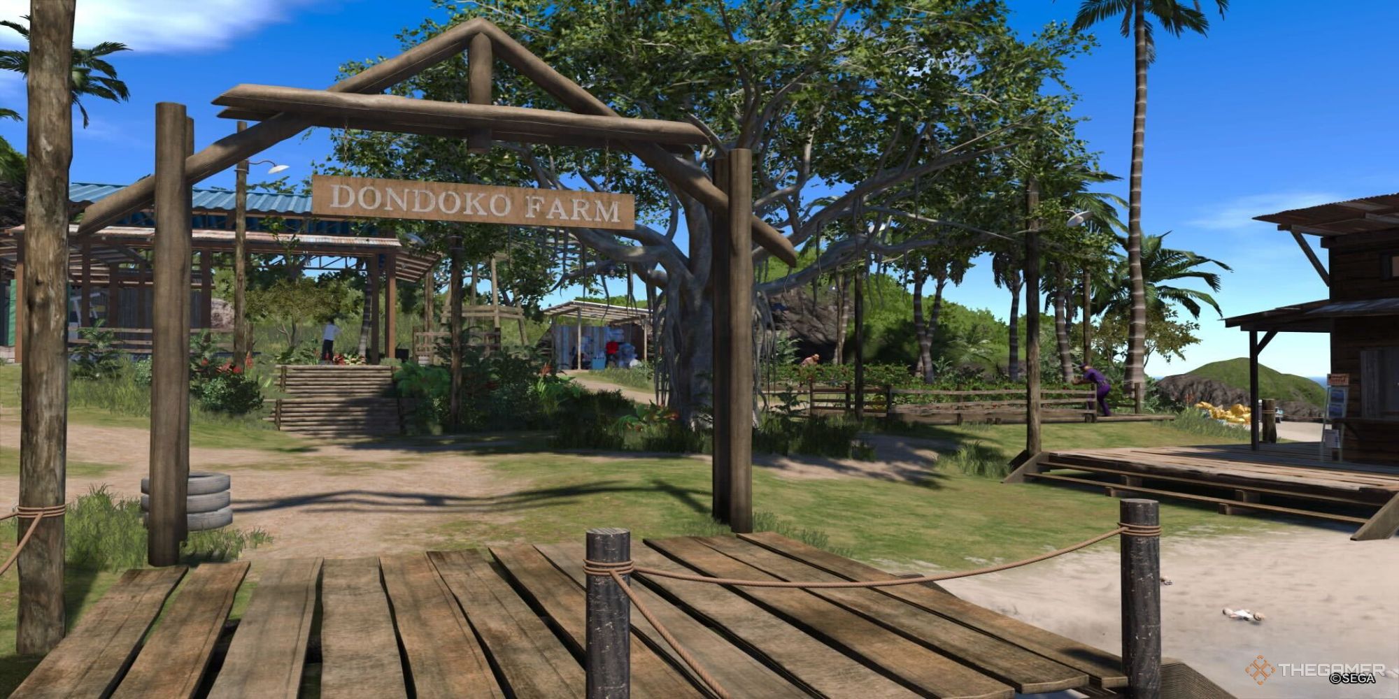A screenshot from Like a Dragon Infinite Wealth showing the entrance to Dondoko Farm, with the sign immediately ahead and men tending fields seen in the distance