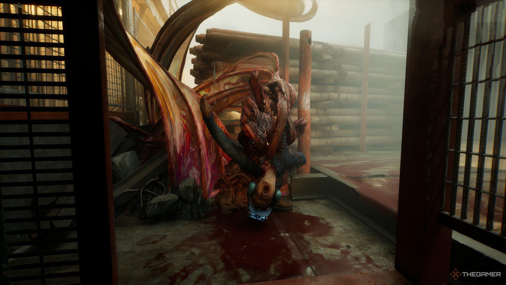 Dead crew member wearing hard hat, unidentifiable, wrapped in the fleshy ribbons of the evil creature, upside down with blood pooled underneath in Still Wakes The Deep.