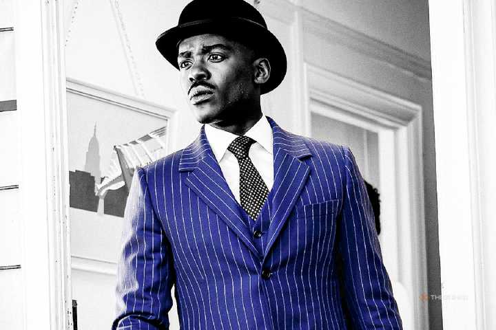 Black and white photo of Ncuti Gatwa in Doctor Who, but his suit is coloured blue.