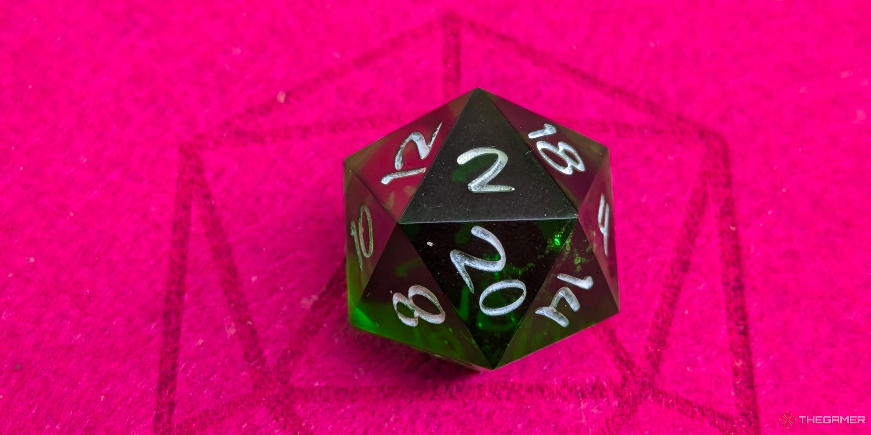 A close up shot of a D20 on red felt, showing a 2.