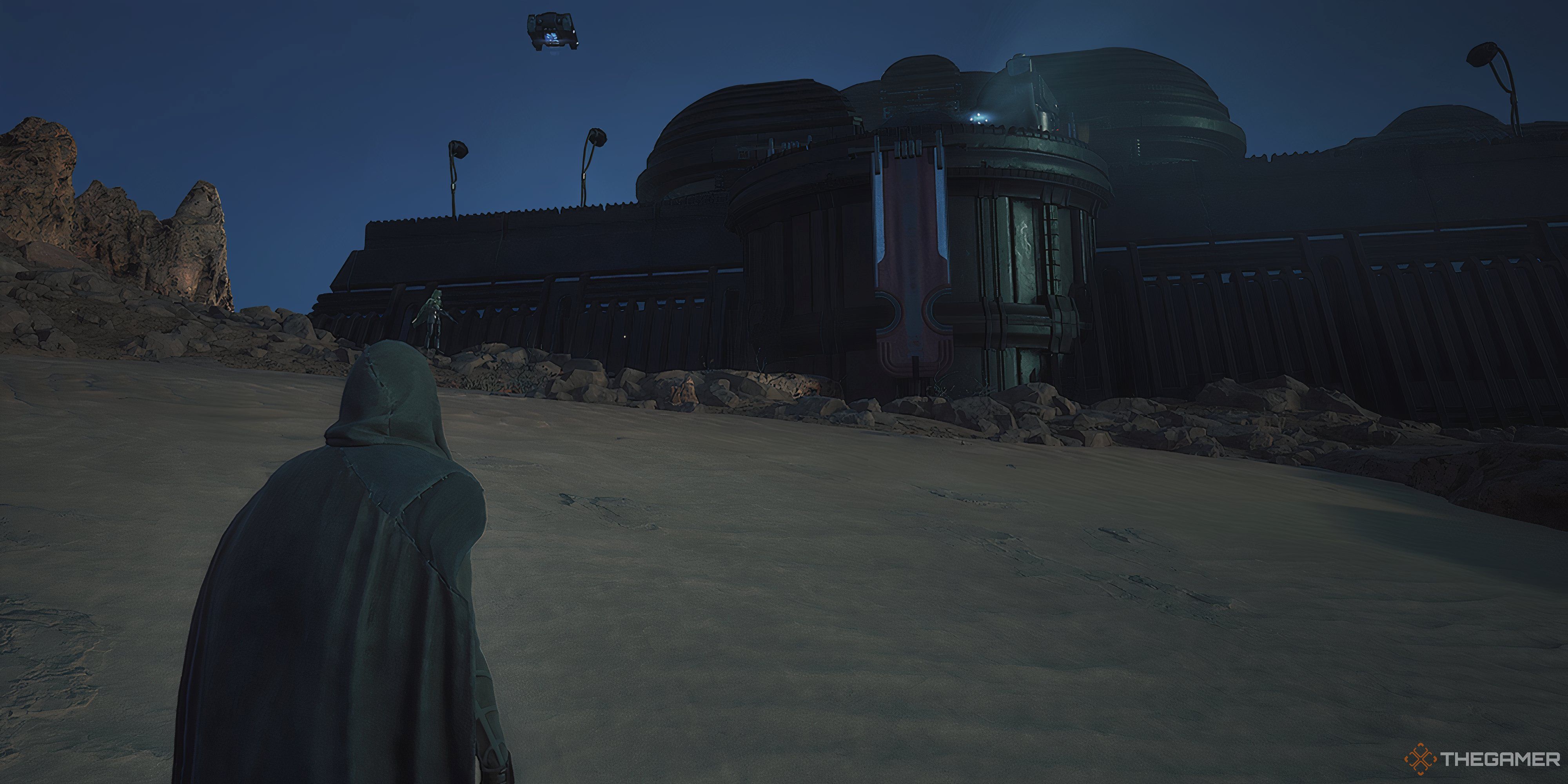 Player looking at the front of the Edge of Acheron stronghold in Dune: Awakening. There is an enemy NPC on the left just ahead of the player.