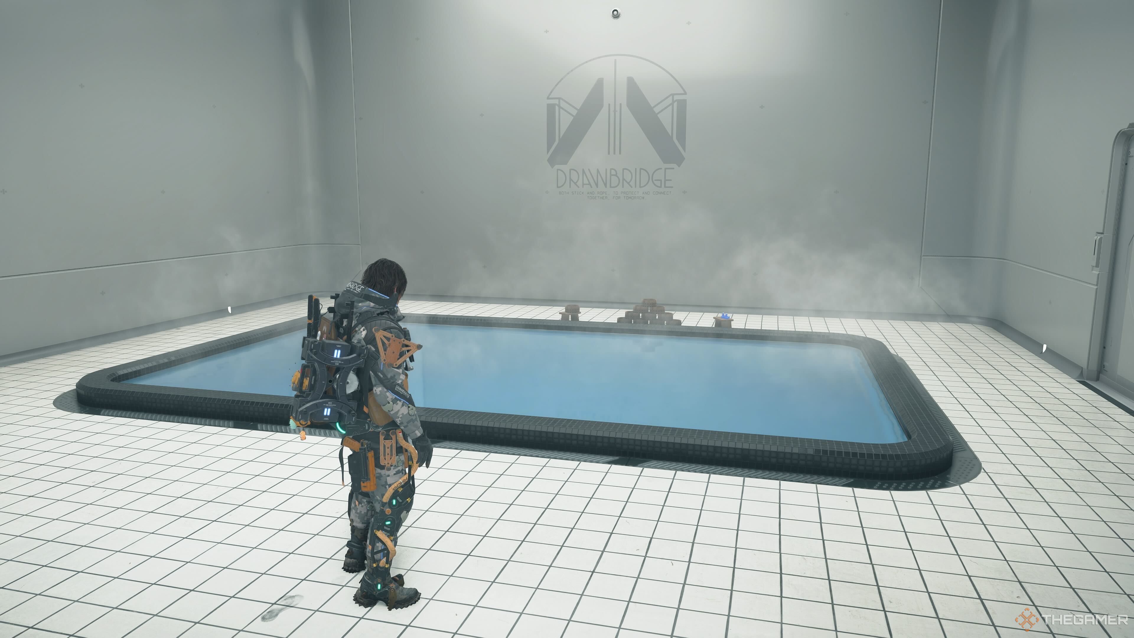 Sam stands next to a hot spring located at Heartman's Lab in Death Stranding 2. 