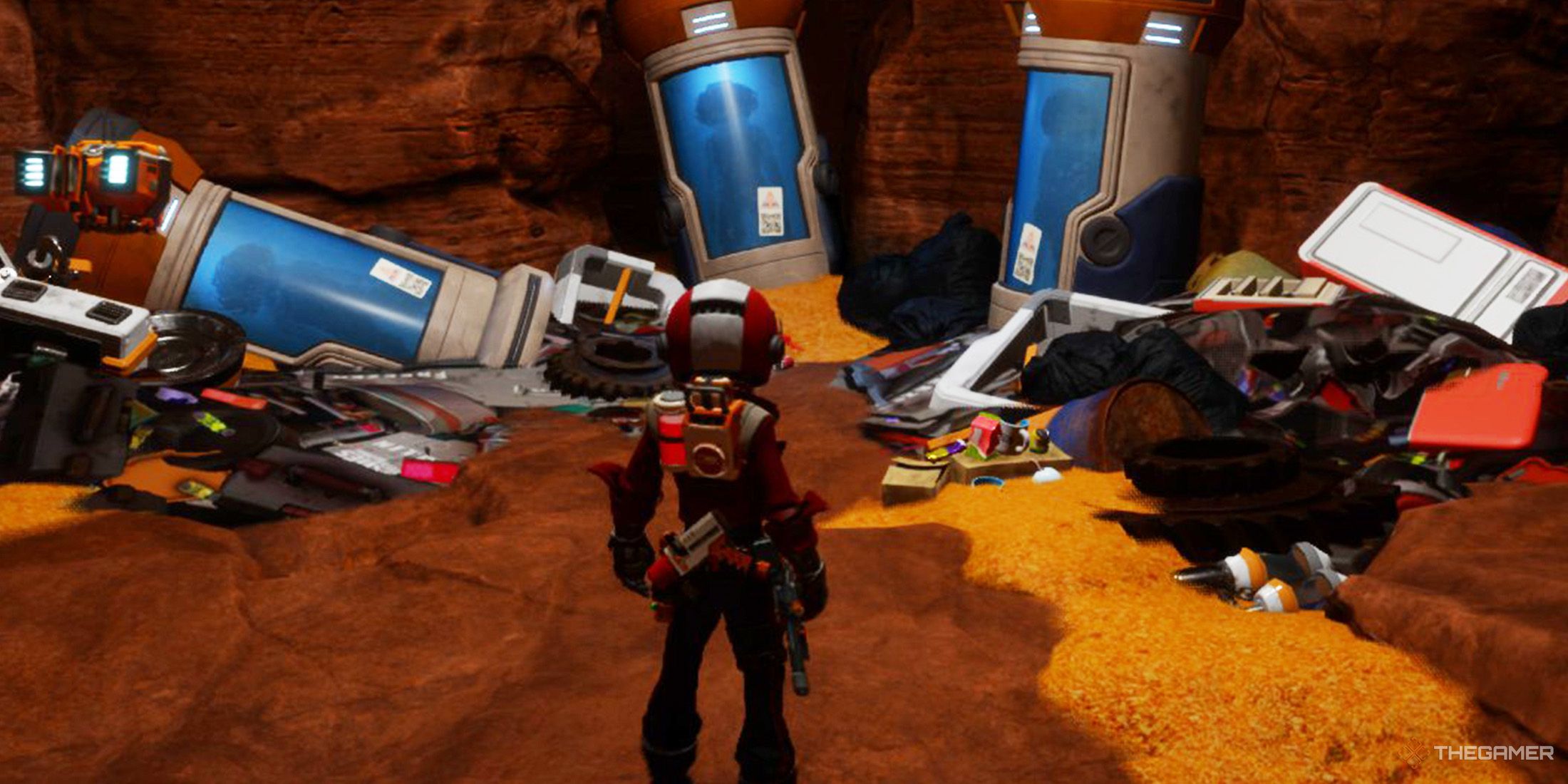 The player is standing in front of cry-o-pods inside a desert cave in Revenge of the Savage Planet.