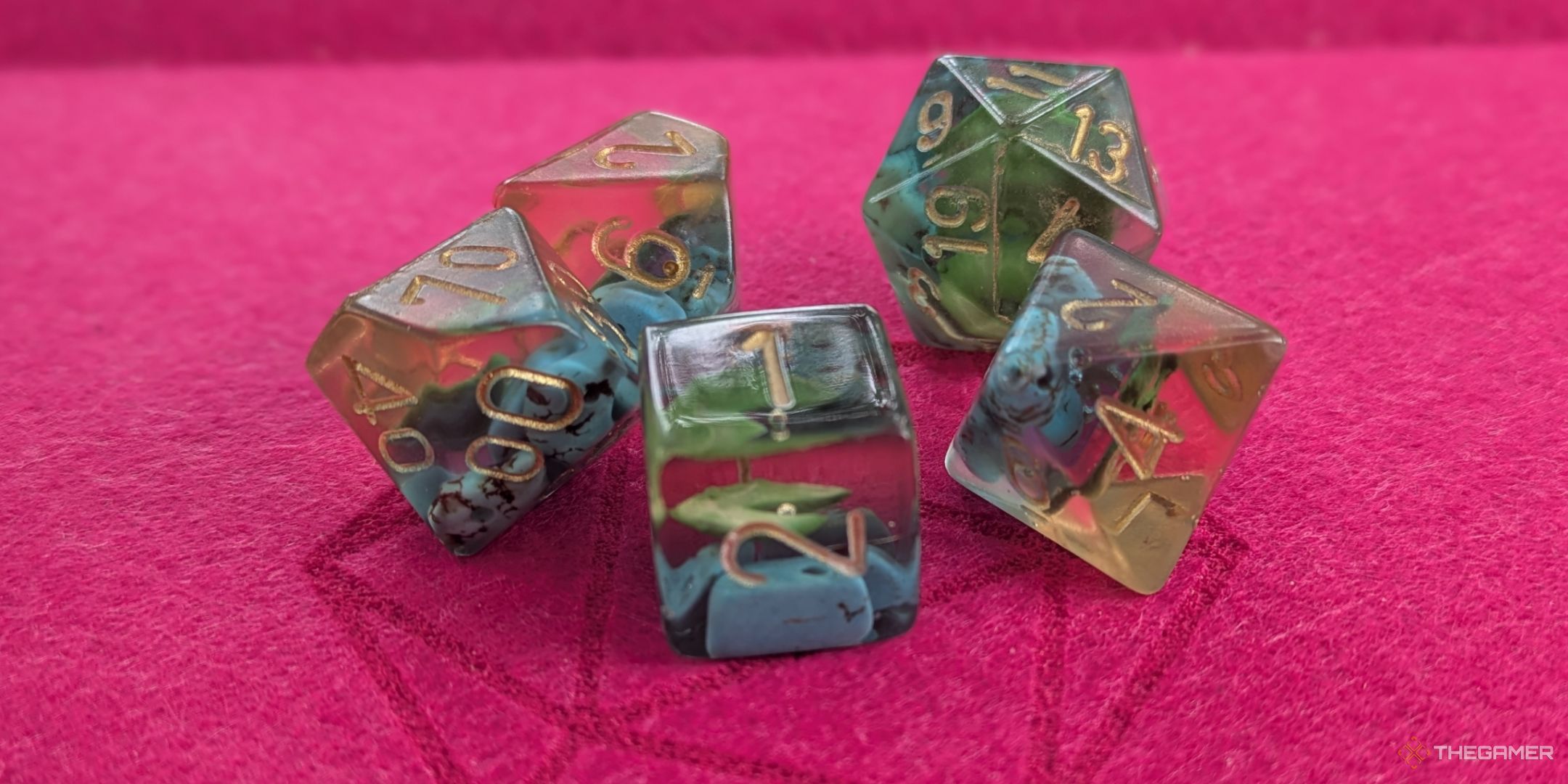 A close up of a set or resin dice, the inside contains small aquamarines and a lily pad.