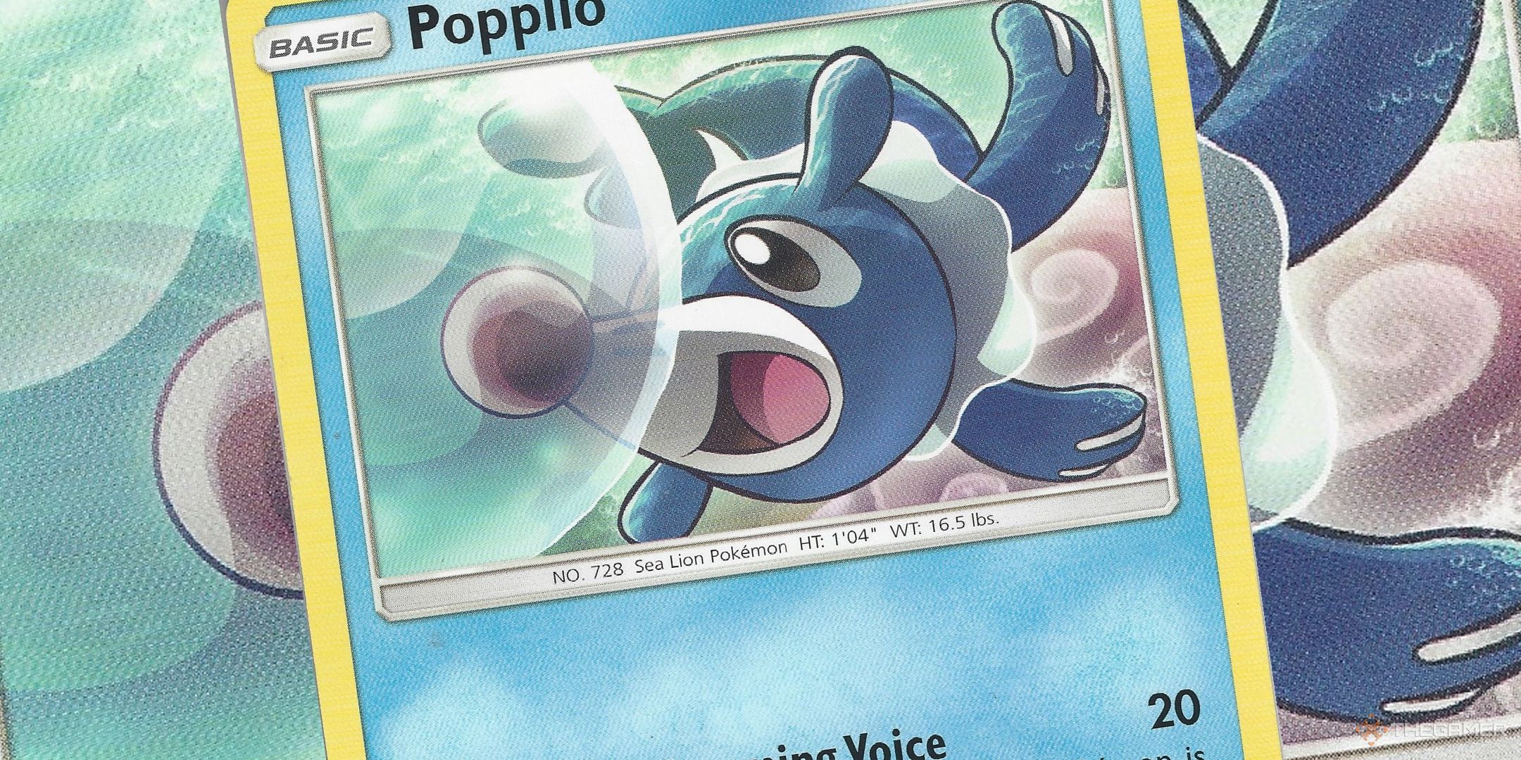 Popplio Pokemon card laid on top of of a larger version of the same card.