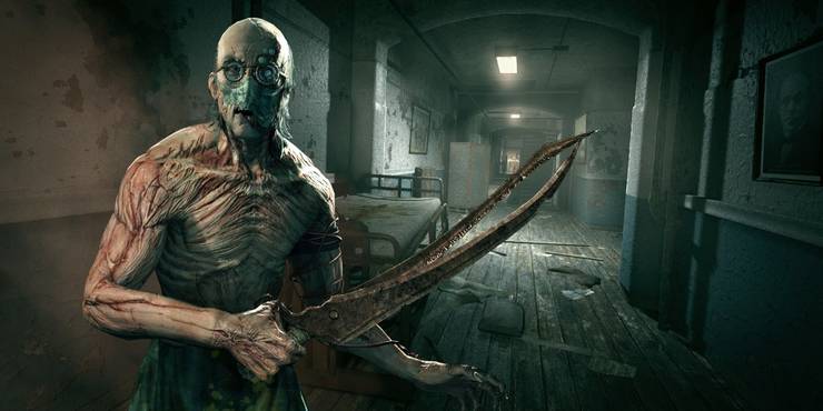 Trager holding a weapon and looking at the camera in the asylum hallway in Outlast