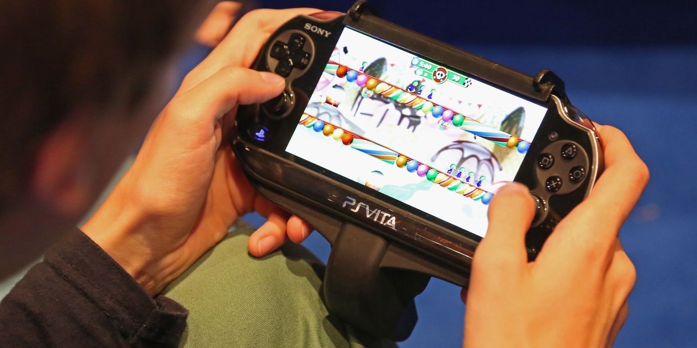 Person with PlayStation Vita in hands away from house