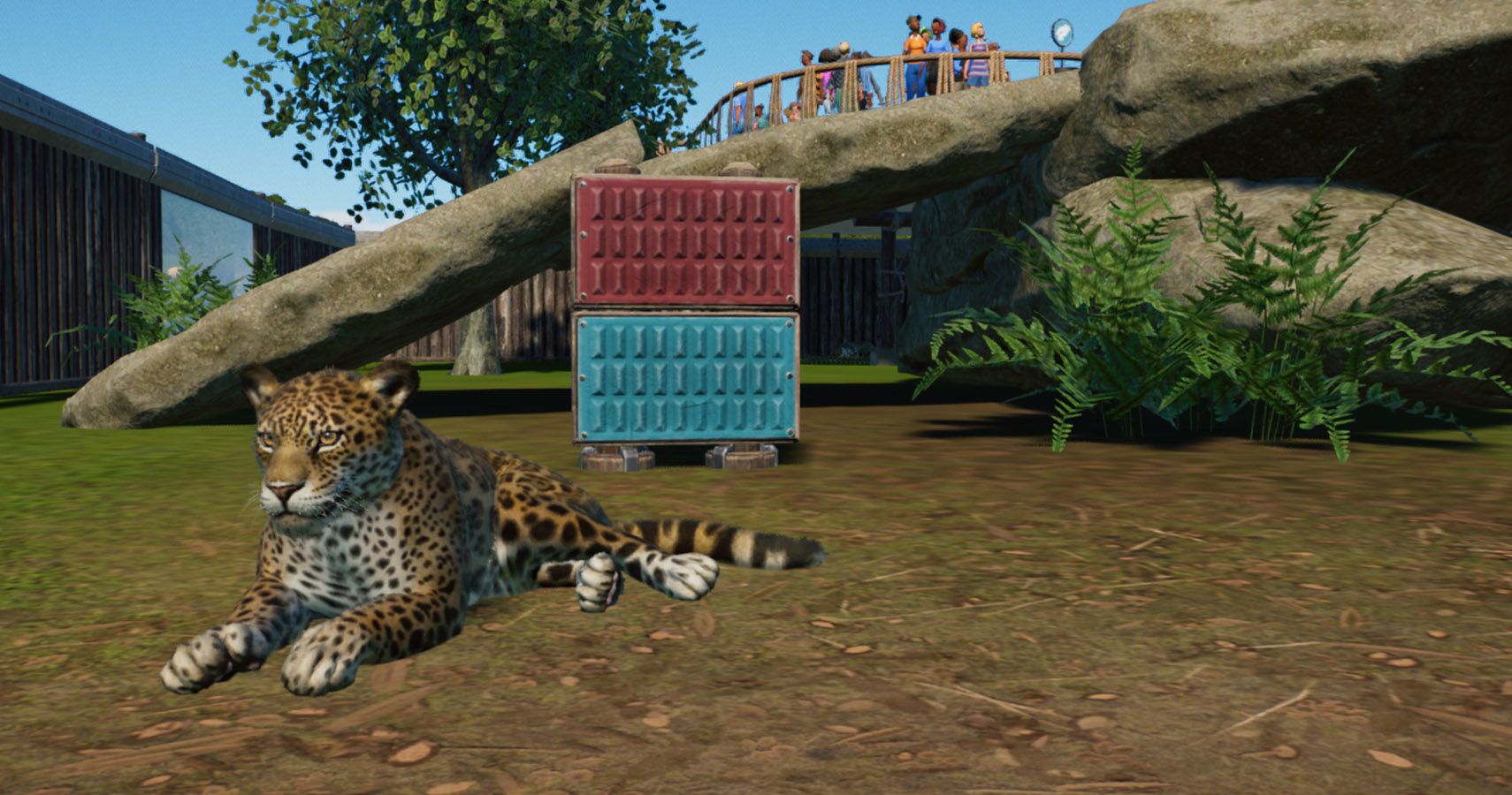 A jaguar sitting down next to a scratching post and rock in its exhibit.