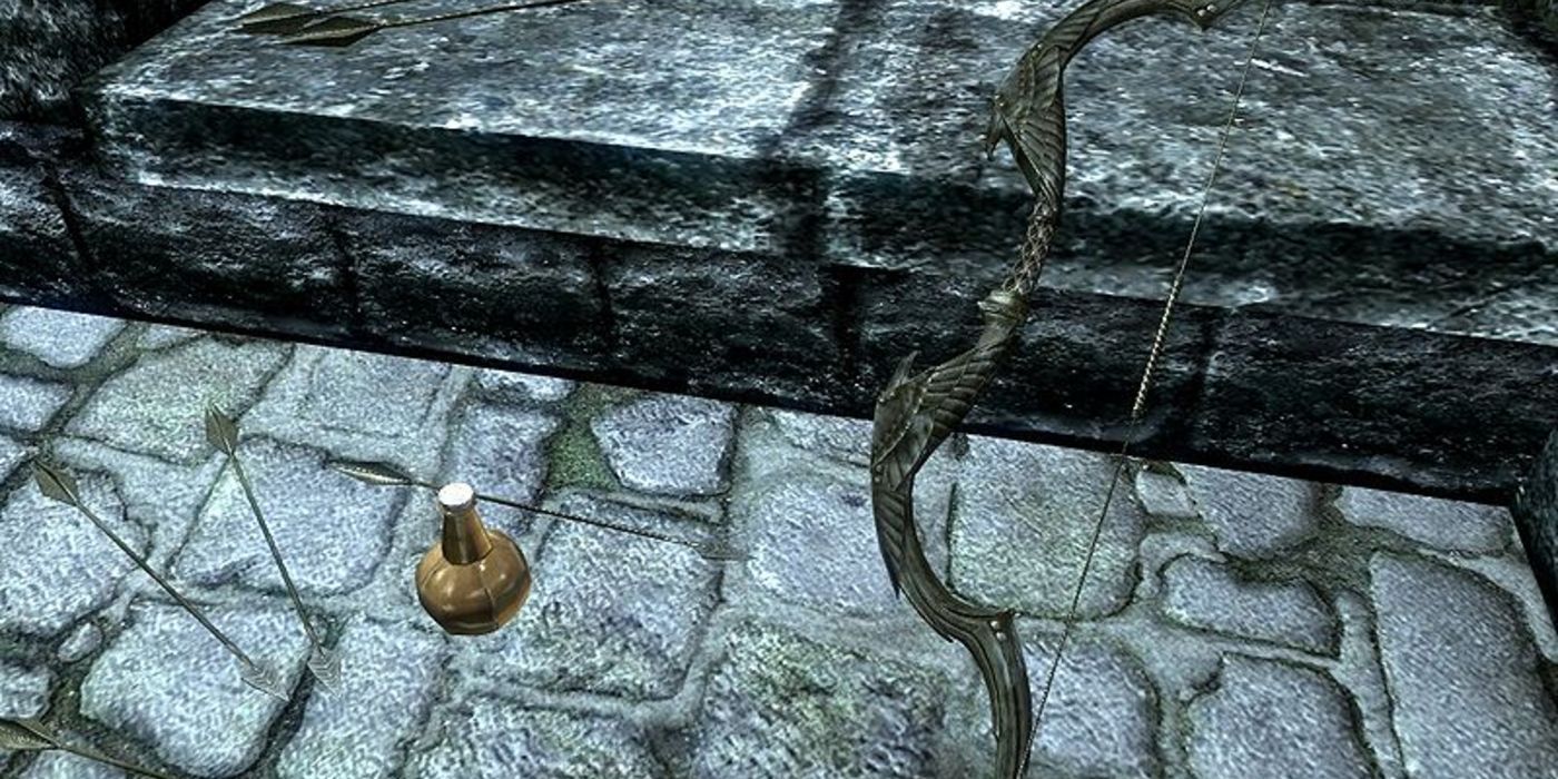 An ornate bow, two arrows and a potion rest against a barrier on a stone wall.